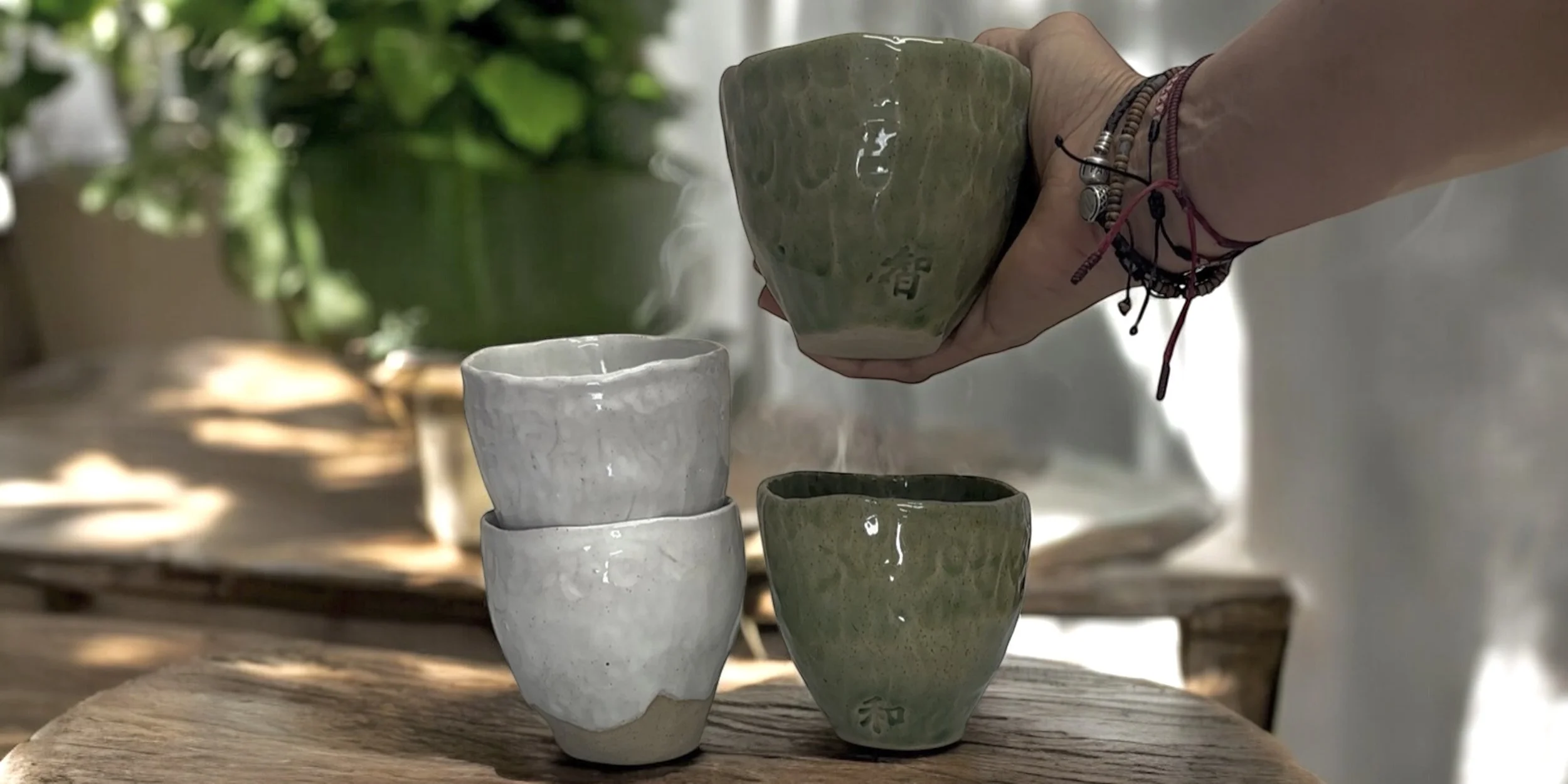 Hand holding a handcrafted stoneware tea bowl with natural texture.