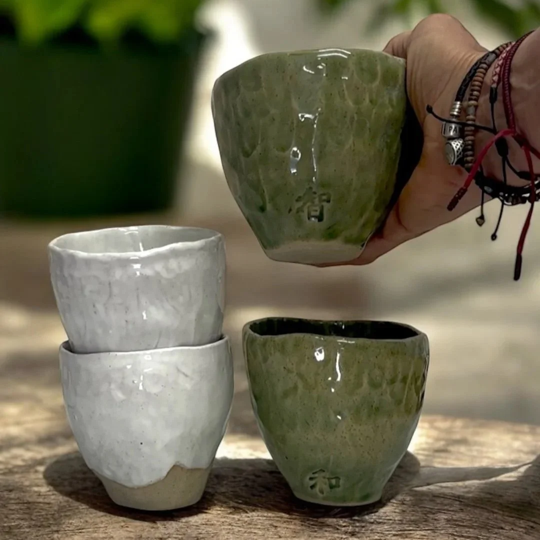 Hand holding a handcrafted stoneware tea bowl with natural texture.