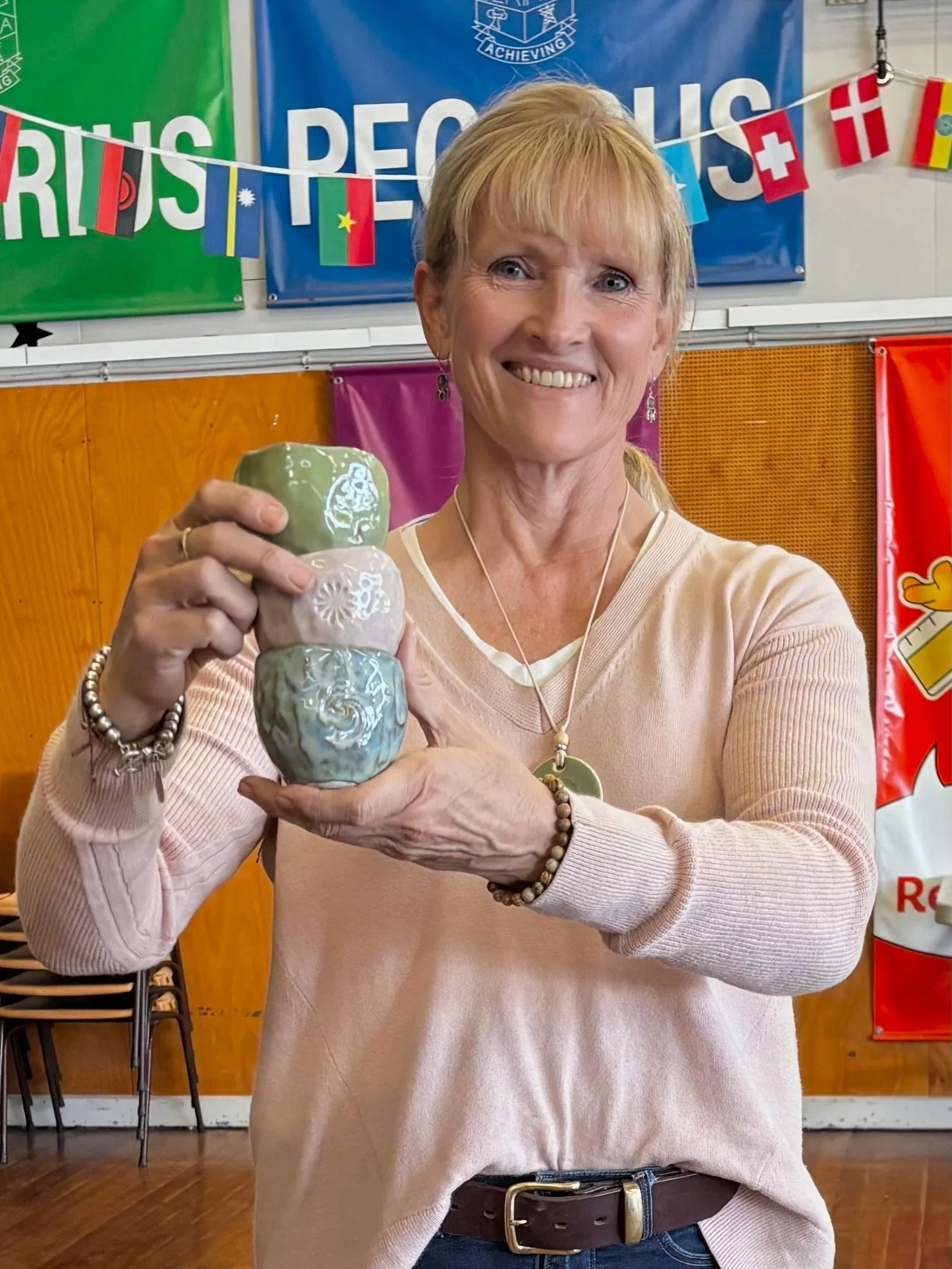 Helen holding a handmade pottery cup during a primary school pottery class