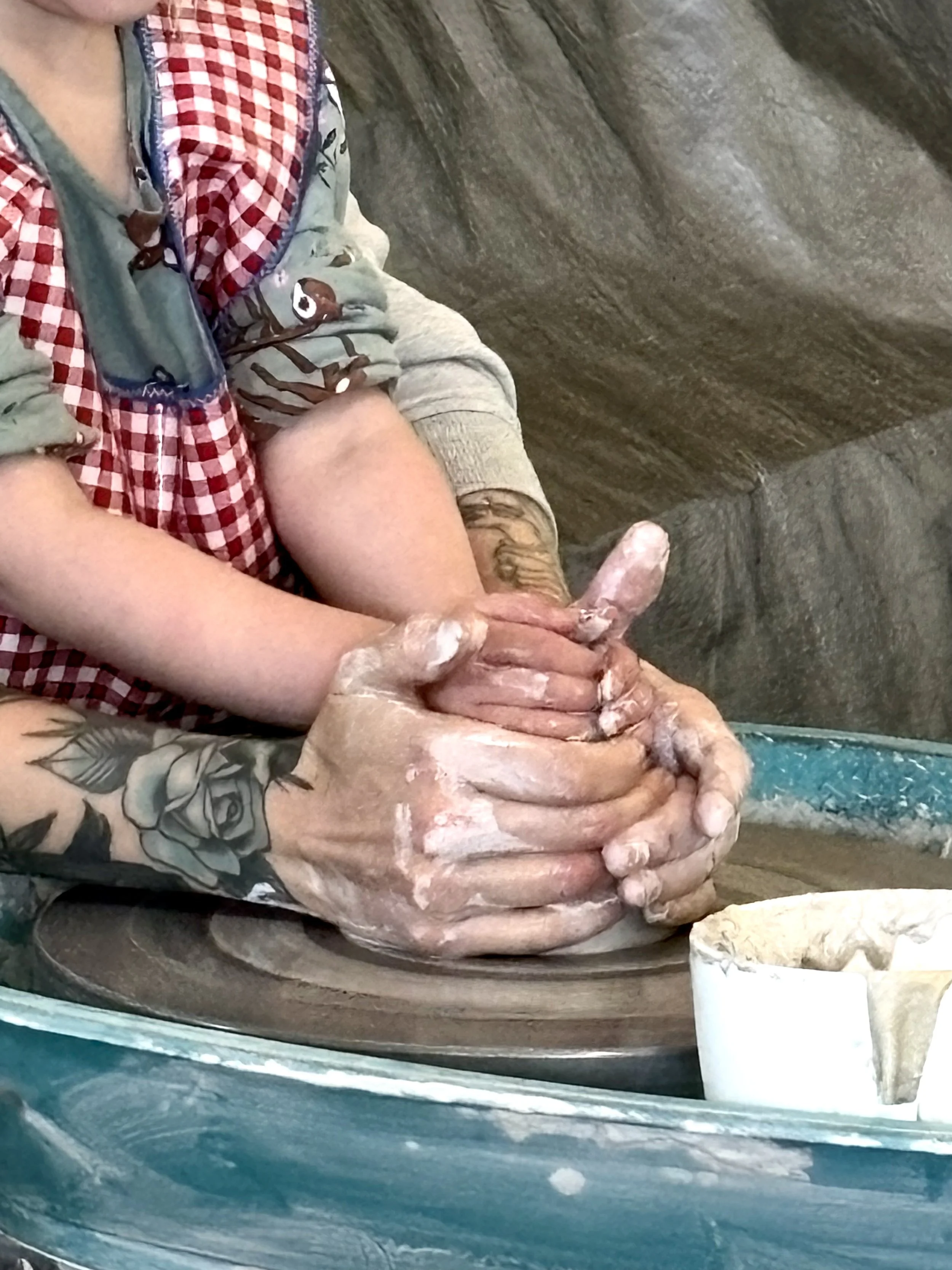 A preschool child’s hands shaping clay on a pottery wheel