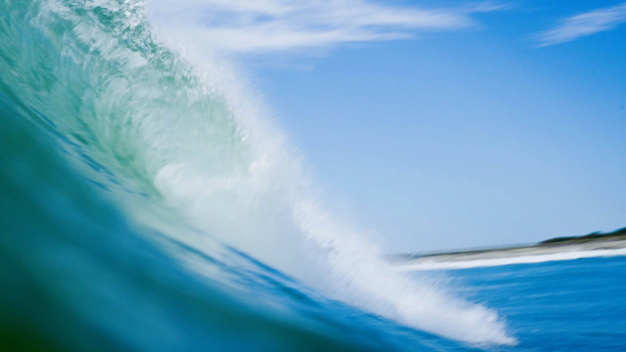 Close-up of an ocean wave curling with blue sky background
