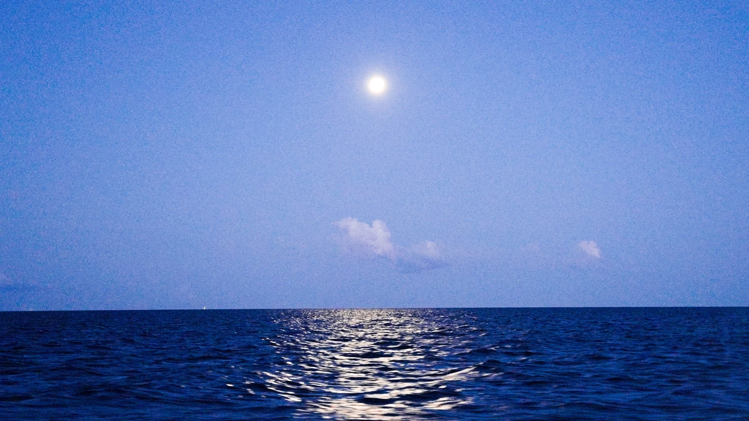 Full moon over ocean with reflection on water surface