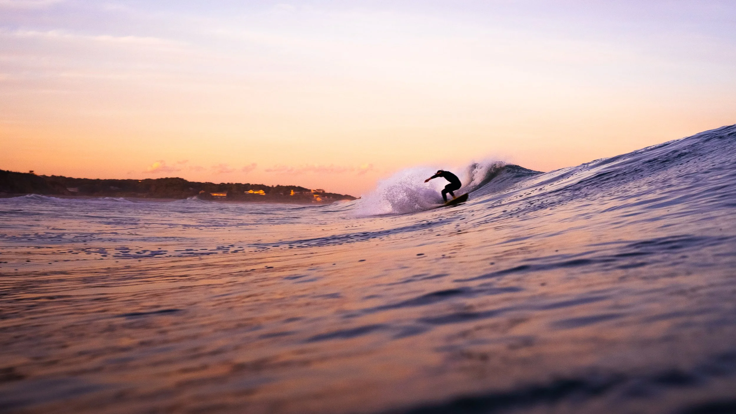 surfer riding a wave at sunset