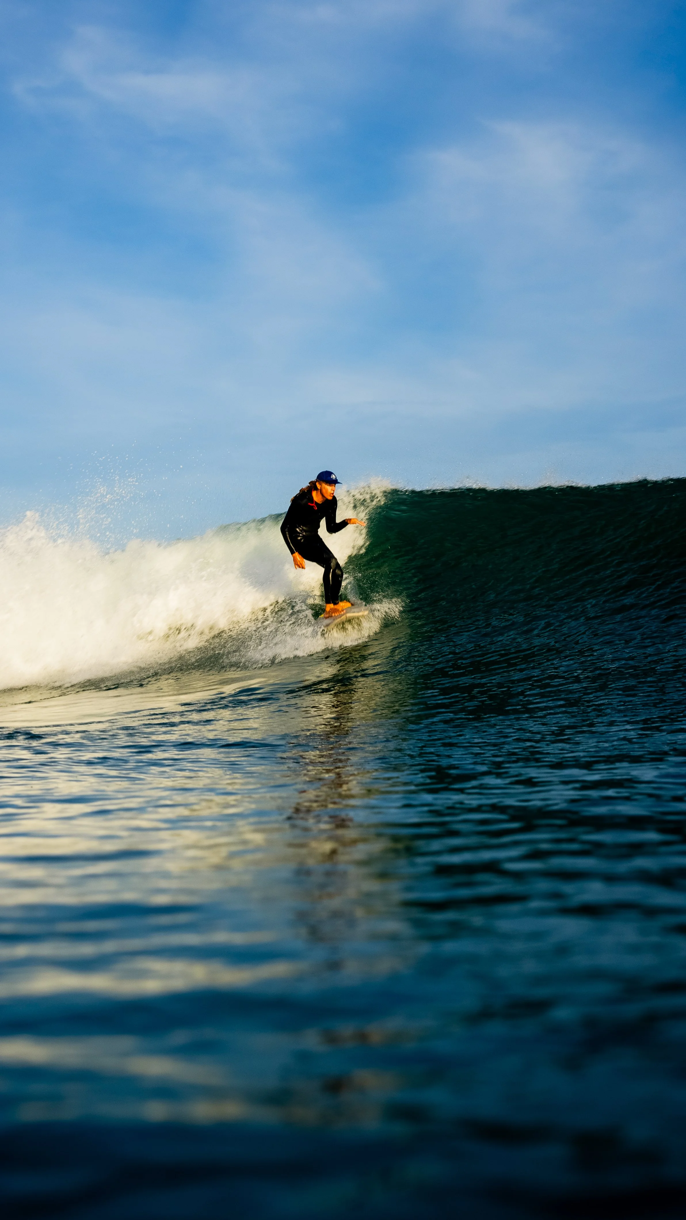 Surfer riding a wave in the ocean at sunset.