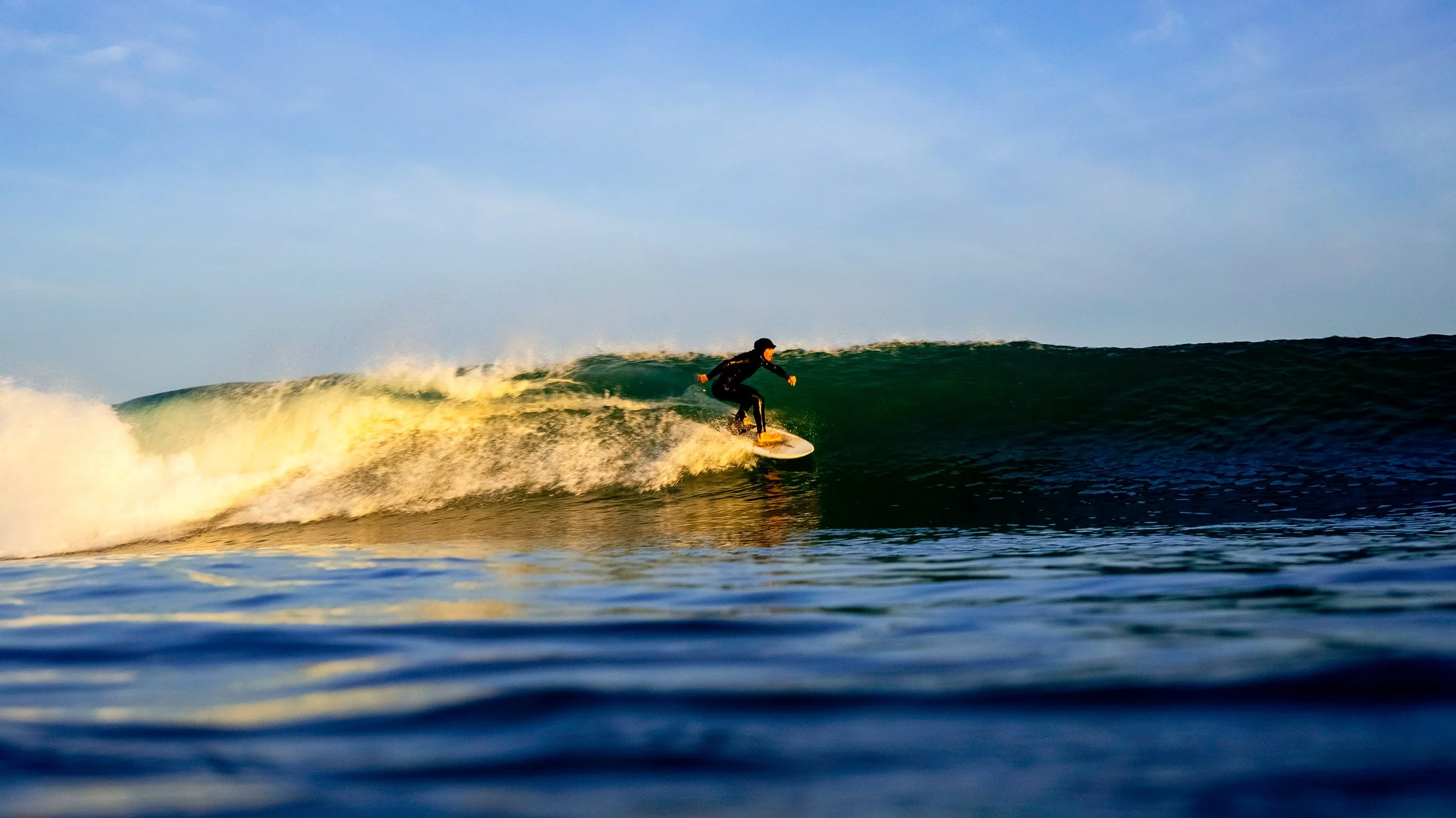 Surfer riding a wave at sunset.