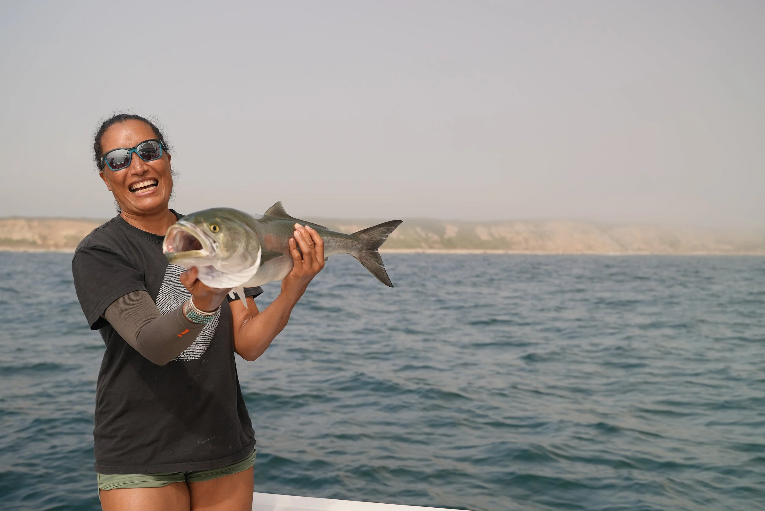 Person holding a fish on a boat at sea