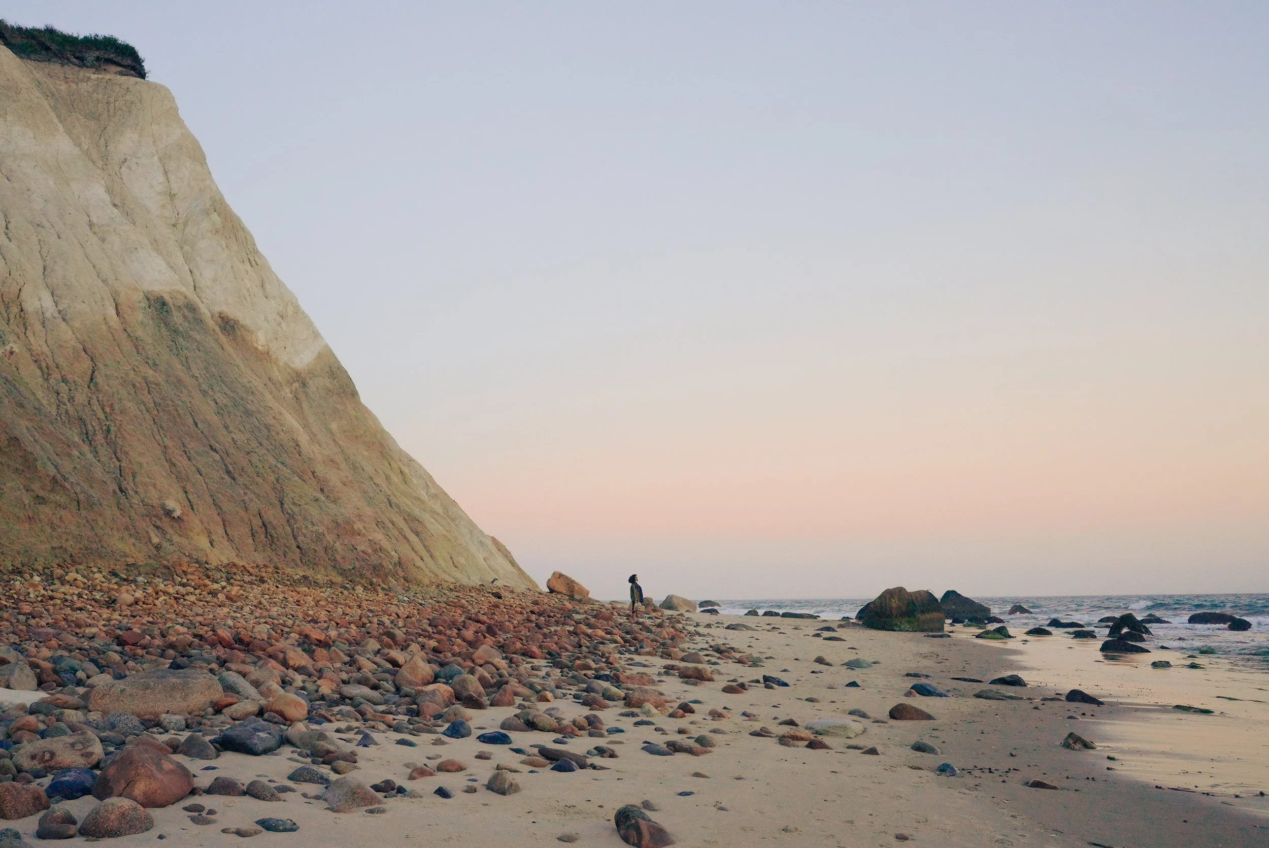 Sunset landscape with rocky beach and steep cliff