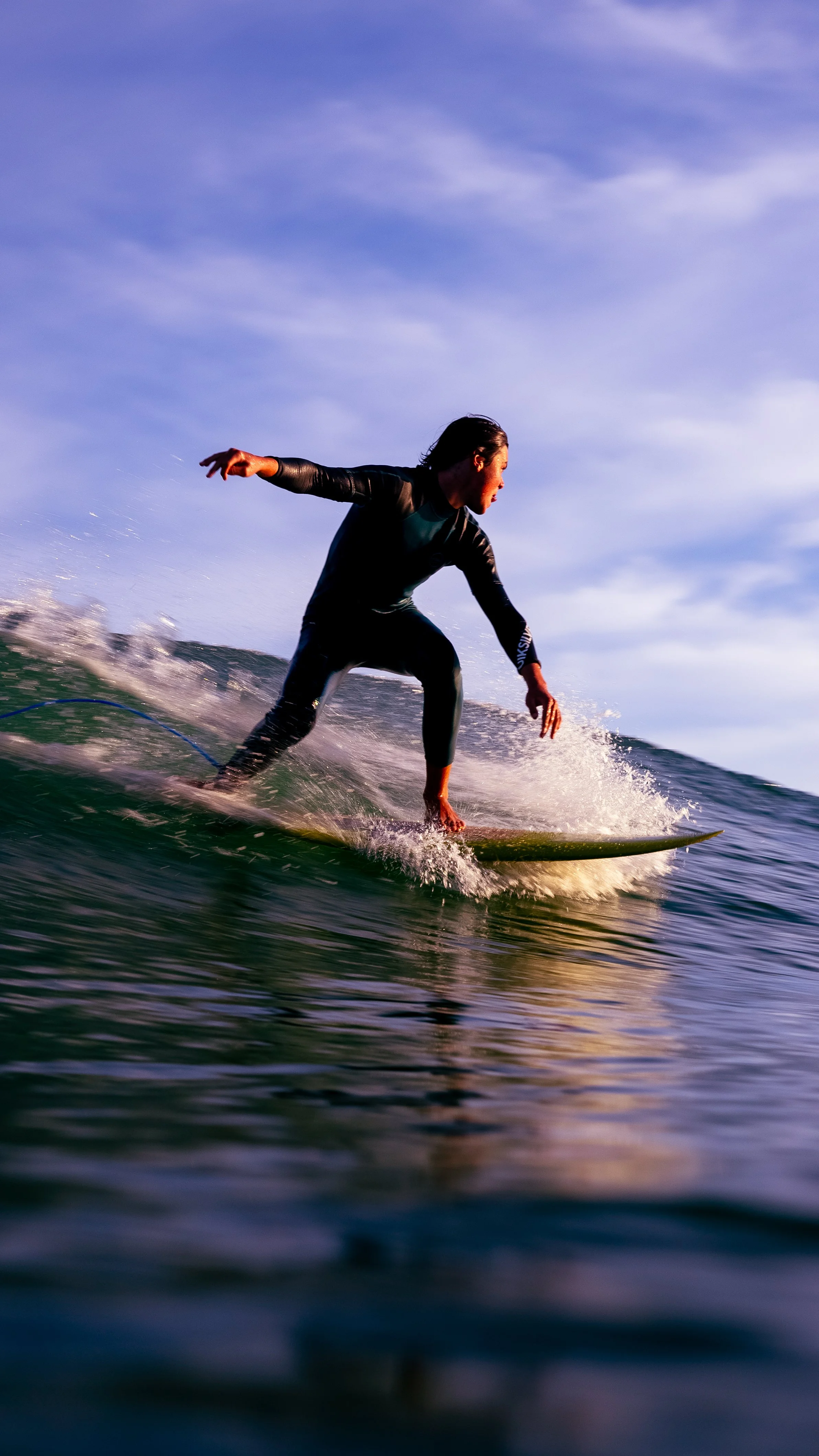 Surfer riding a wave on a surfboard with the ocean and sky in the background.