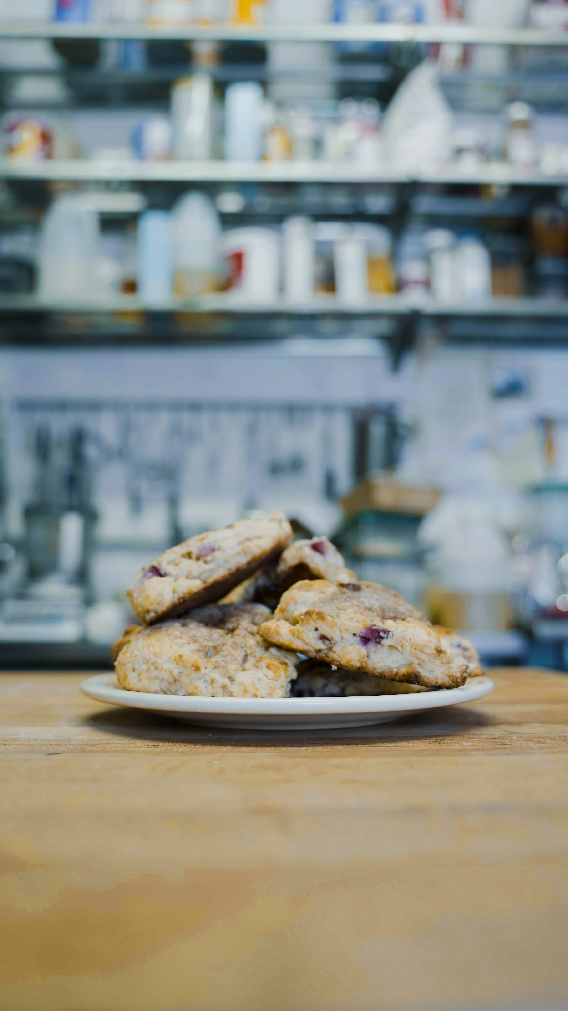 Plate of scones with berries on a wooden table in a kitchen setting.