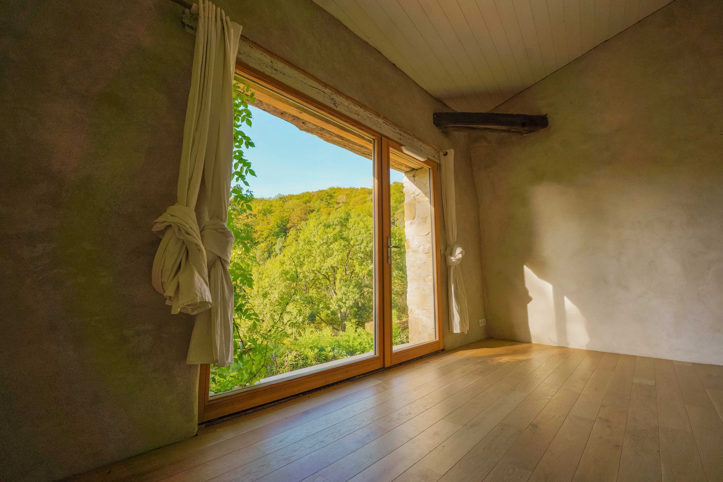 Salle de pratique pour retraite de yoga en Occitanie — Salle lumineuse avec parquet bois, grandes baies vitrées donnant sur la nature et équipements pour yoga, méditation et stages, dans un gîte de groupe proche de Toulouse.