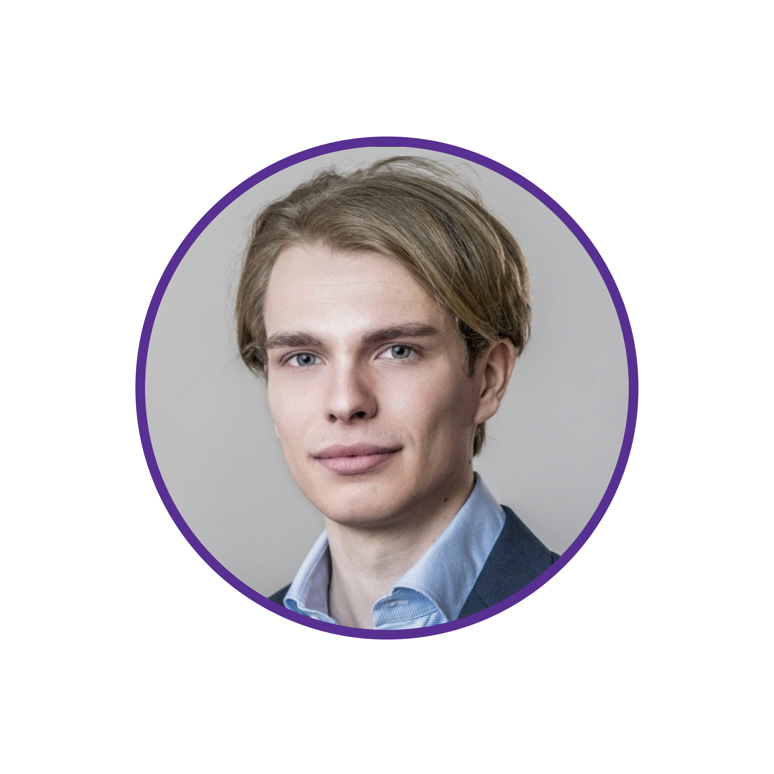 Headshot of a young man with light brown hair and blue eyes, wearing a suit and light blue shirt, against a plain gray background.