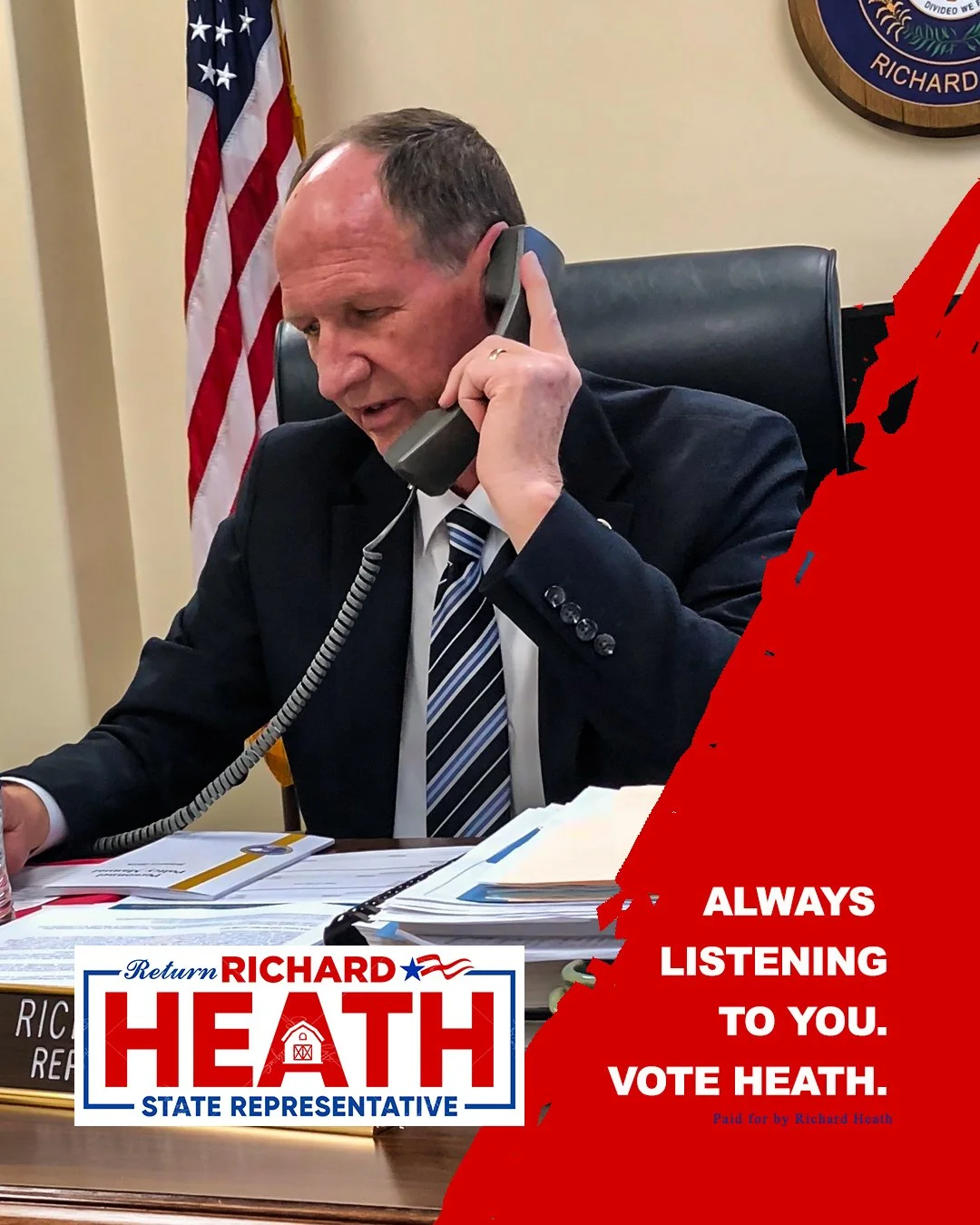 A man in a suit is sitting at a desk, talking on a landline phone, with an American flag behind him. There are documents on the desk. The poster on the image promotes Richard Heath, a state representative candidate, with the slogan 'Always listening 