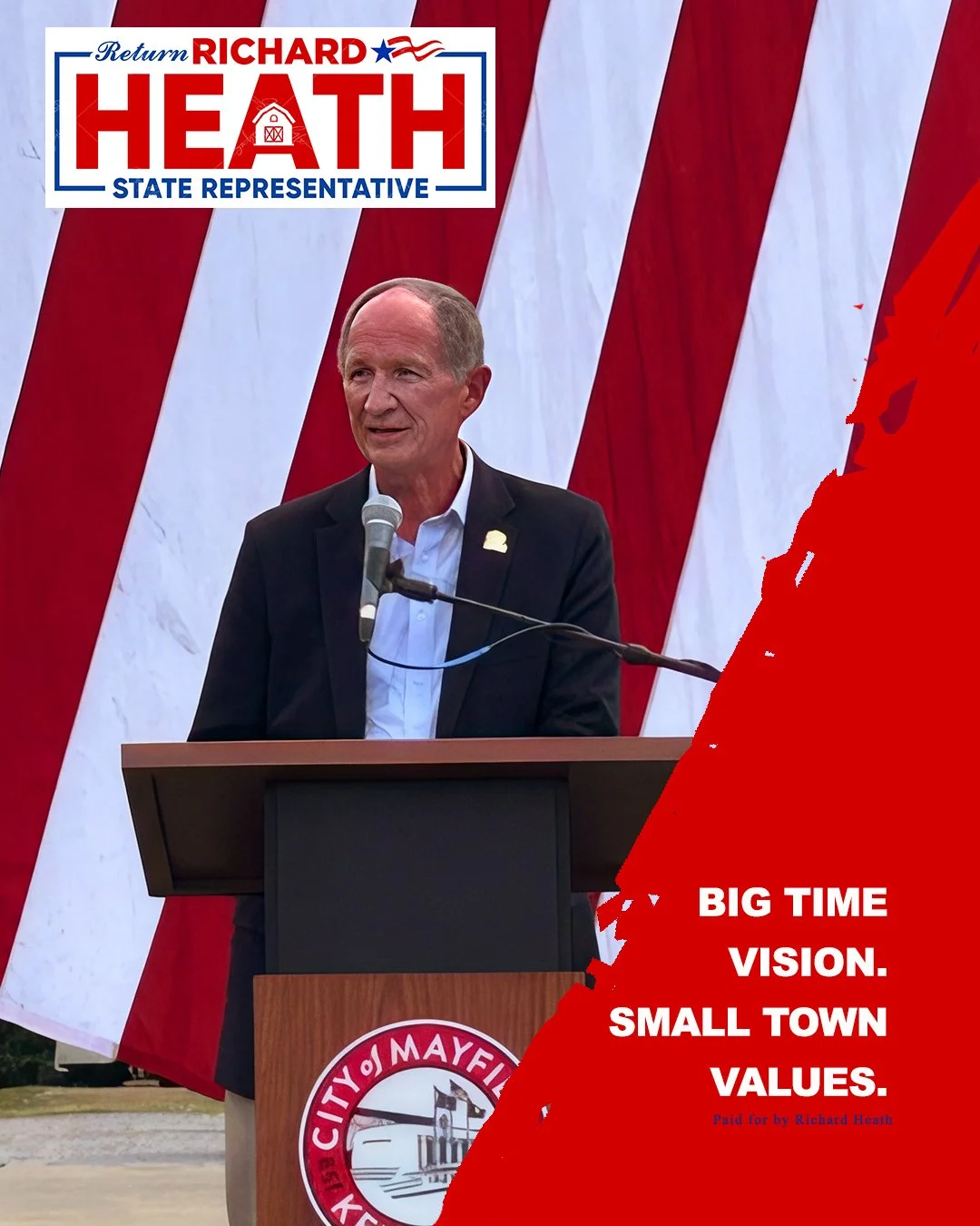 A man in a suit speaking at a podium with a microphone, standing in front of a backdrop of large red and white stripes. A sign on the top left reads 'Return Richard Heath, State Representative.' Part of a logo for Mayfield City is visible on the podi