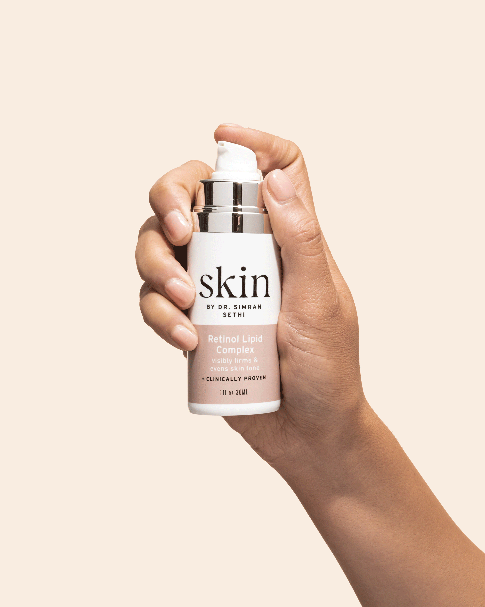 A hand holding a bottle of skincare product labeled 'Skin by Dr. Simran Sethi, Retinol Lipid Complex, visibly firms & evens skin tone, clinically proven, 1 fl oz 30 ml.'