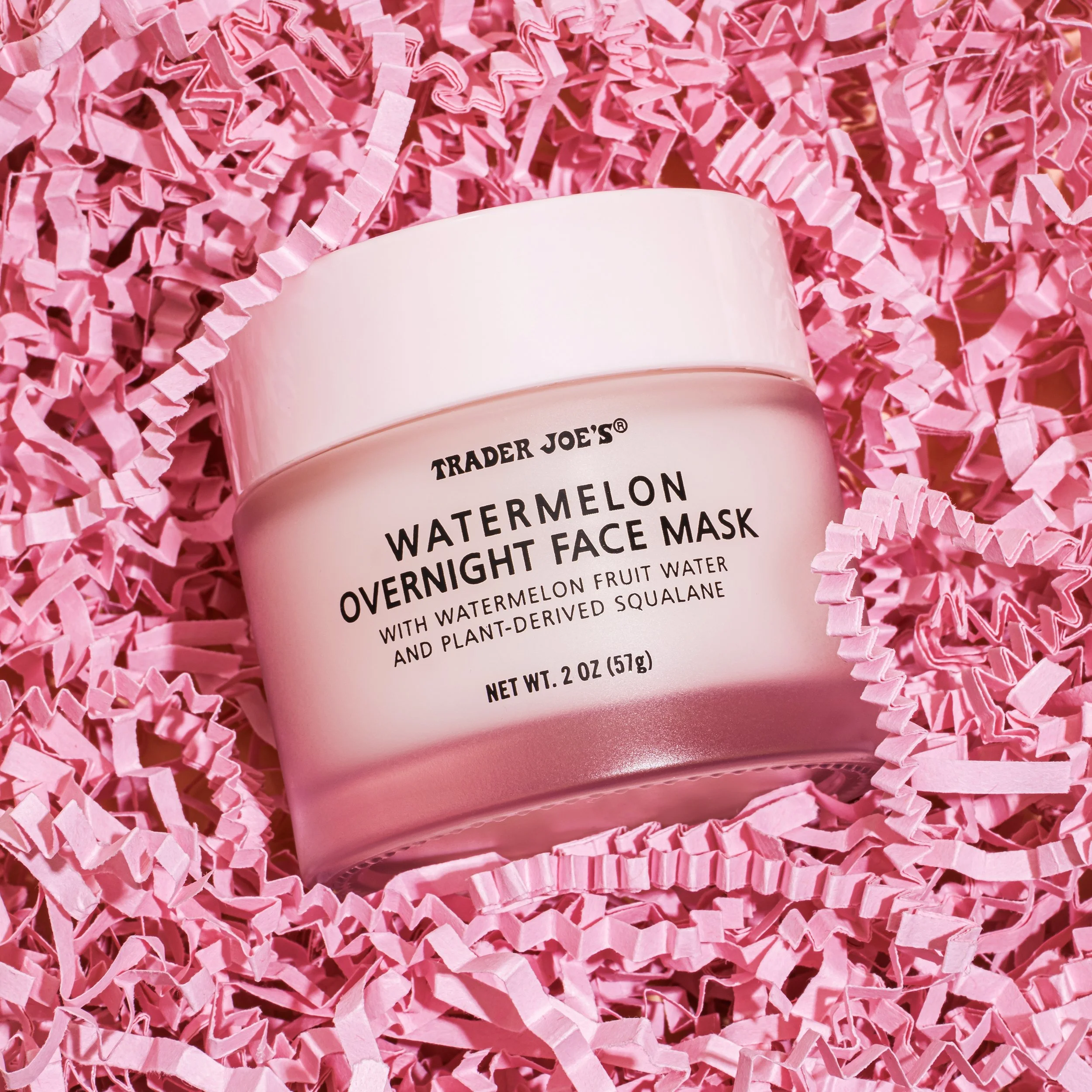 A pink container of Trader Joe's Watermelon Overnight Face Mask surrounded by pink shredded paper.