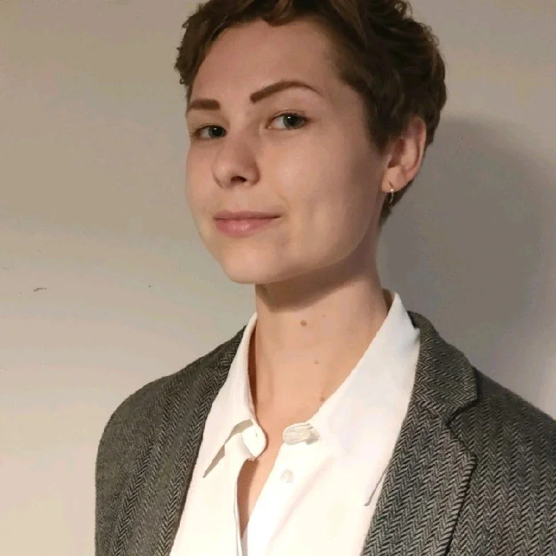 A non-binary human with pale skin, a short pixie crop, and a white loose collared shirt
