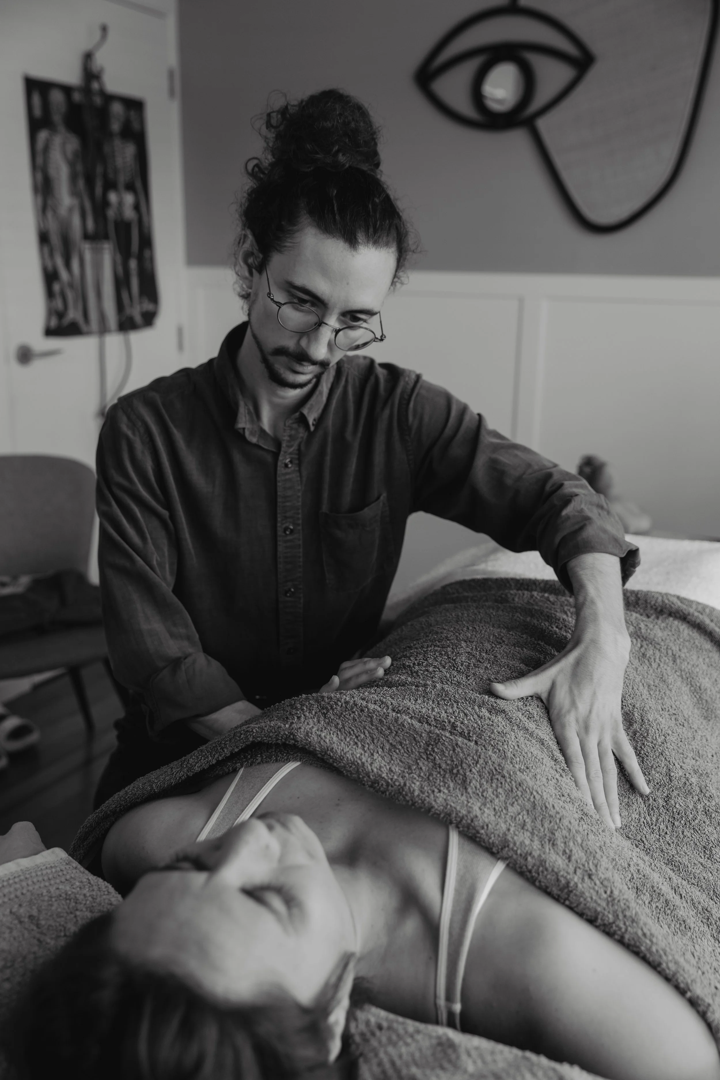 Kaspara Chaise gives an osteopathic treatment to a patient lying on the treatment table. His hands are feeling either side of the patient's ribs.