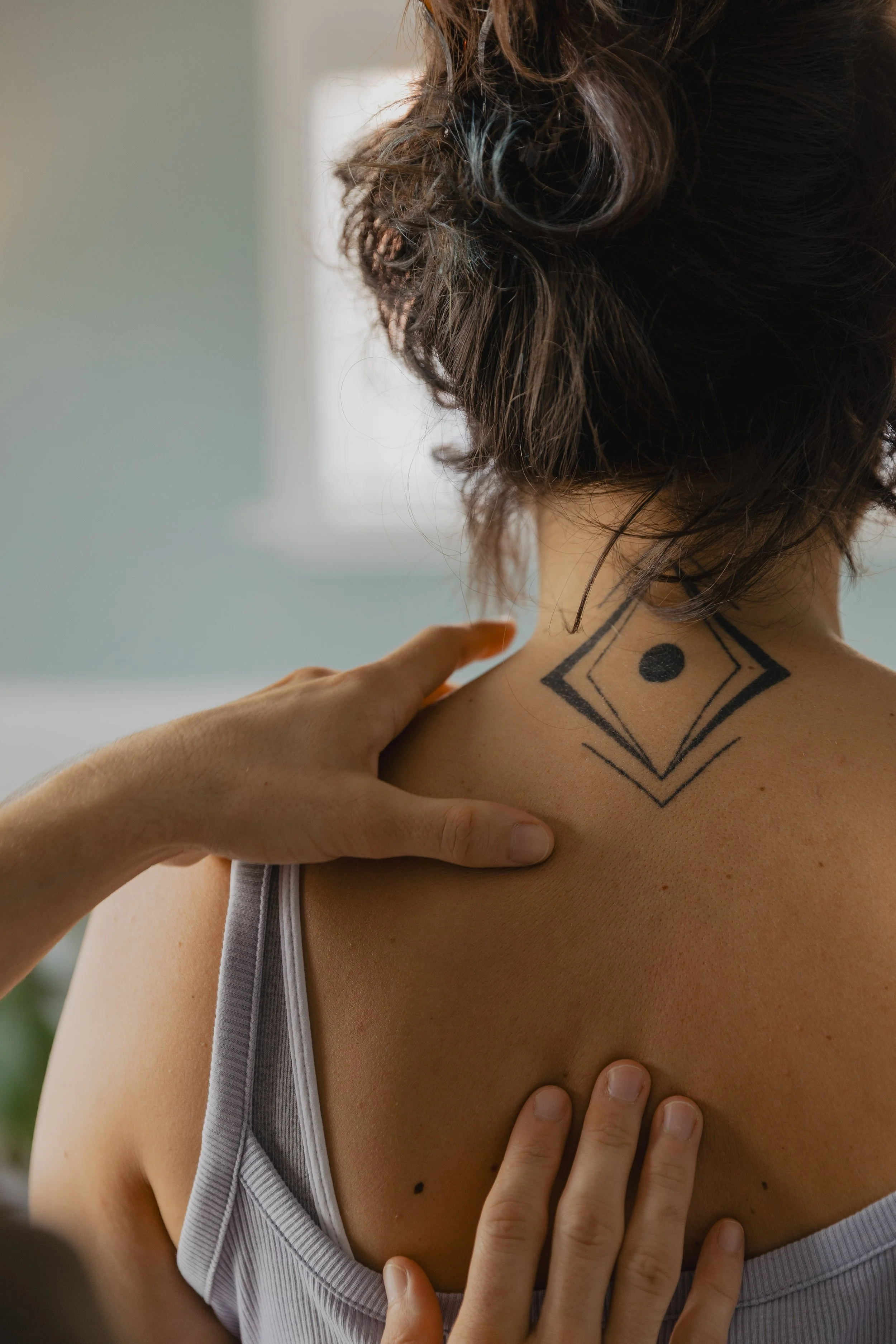 Kaspara palpates the back of a patient's neck during an osteopathic examination.