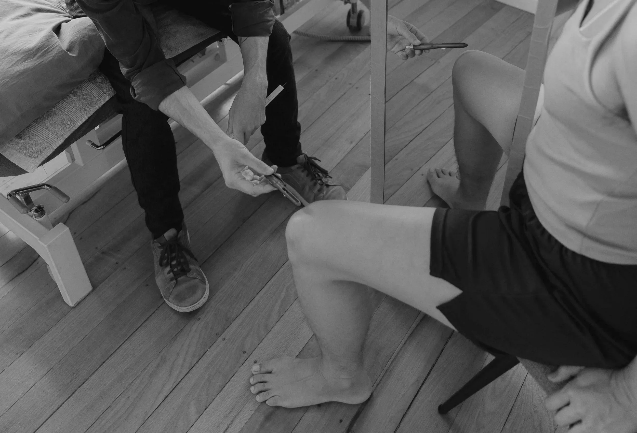 Kaspara Chaise demonstrating mirror therapy for chronic pain with a person sitting on a chair with a mirror reflecting their foot as part of GMI (graded motor imagery)