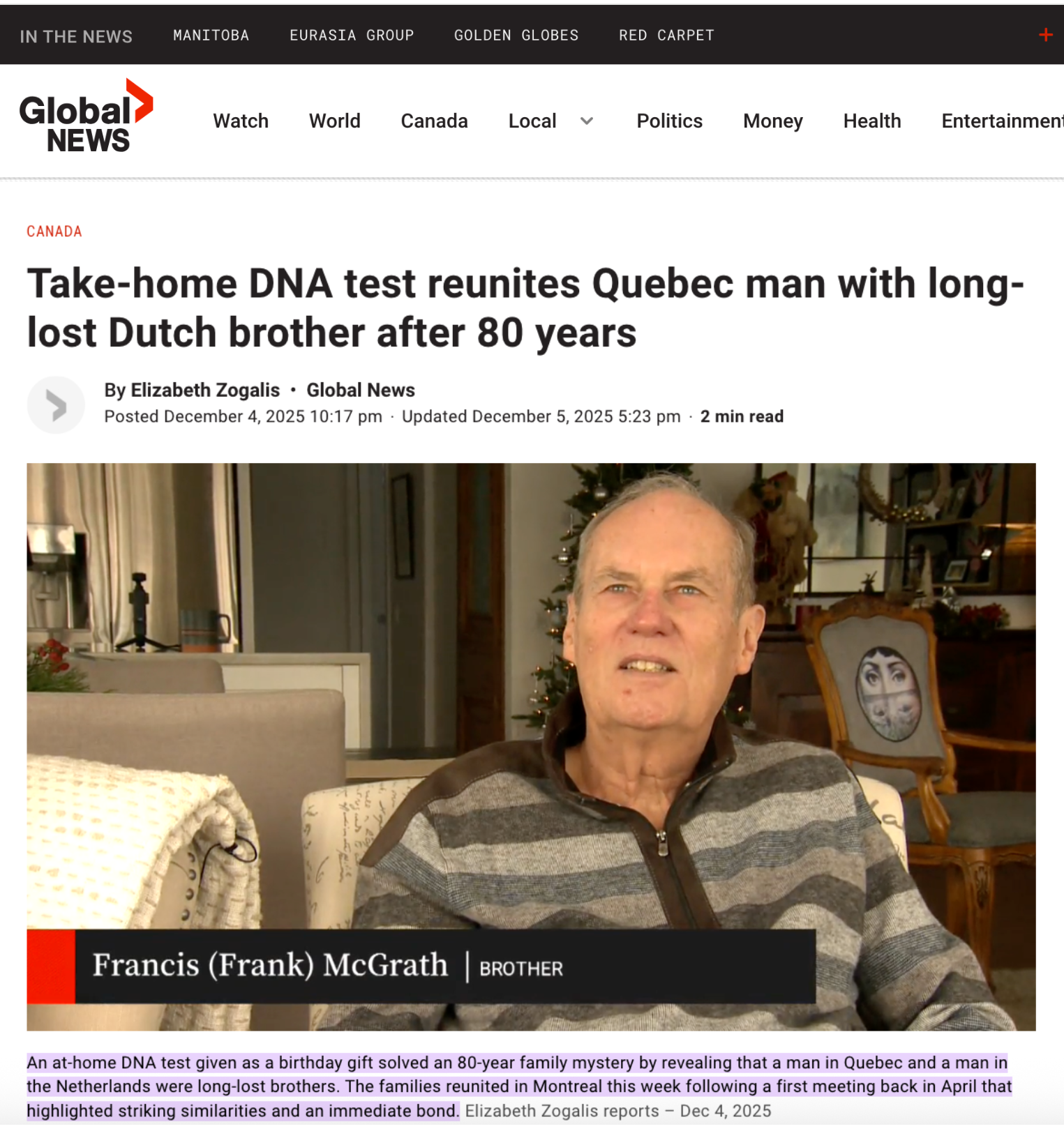 A man with short gray hair, wearing a striped zip-up sweater, sitting indoors with Christmas decorations in the background, including a Christmas tree and festive ornaments.