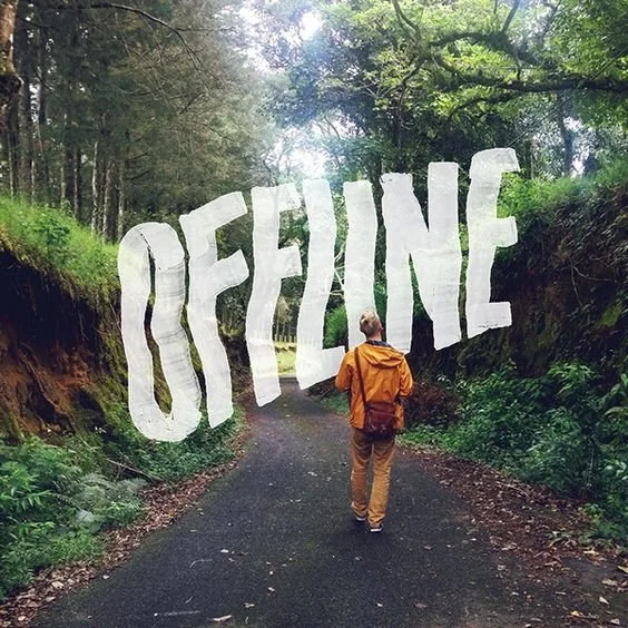 A man wearing a yellow jacket walking on a forest path with a large, white, 3D text that says 'FEELING' leaning on the trees on both sides of the trail.