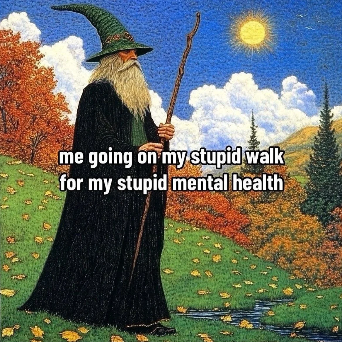 A bearded wizard with a tall green hat with a point, black robe, holding a staff, standing on a grassy hill covered with fallen yellow leaves, with autumn trees and mountains in the background under a bright sun and cloud-filled sky.