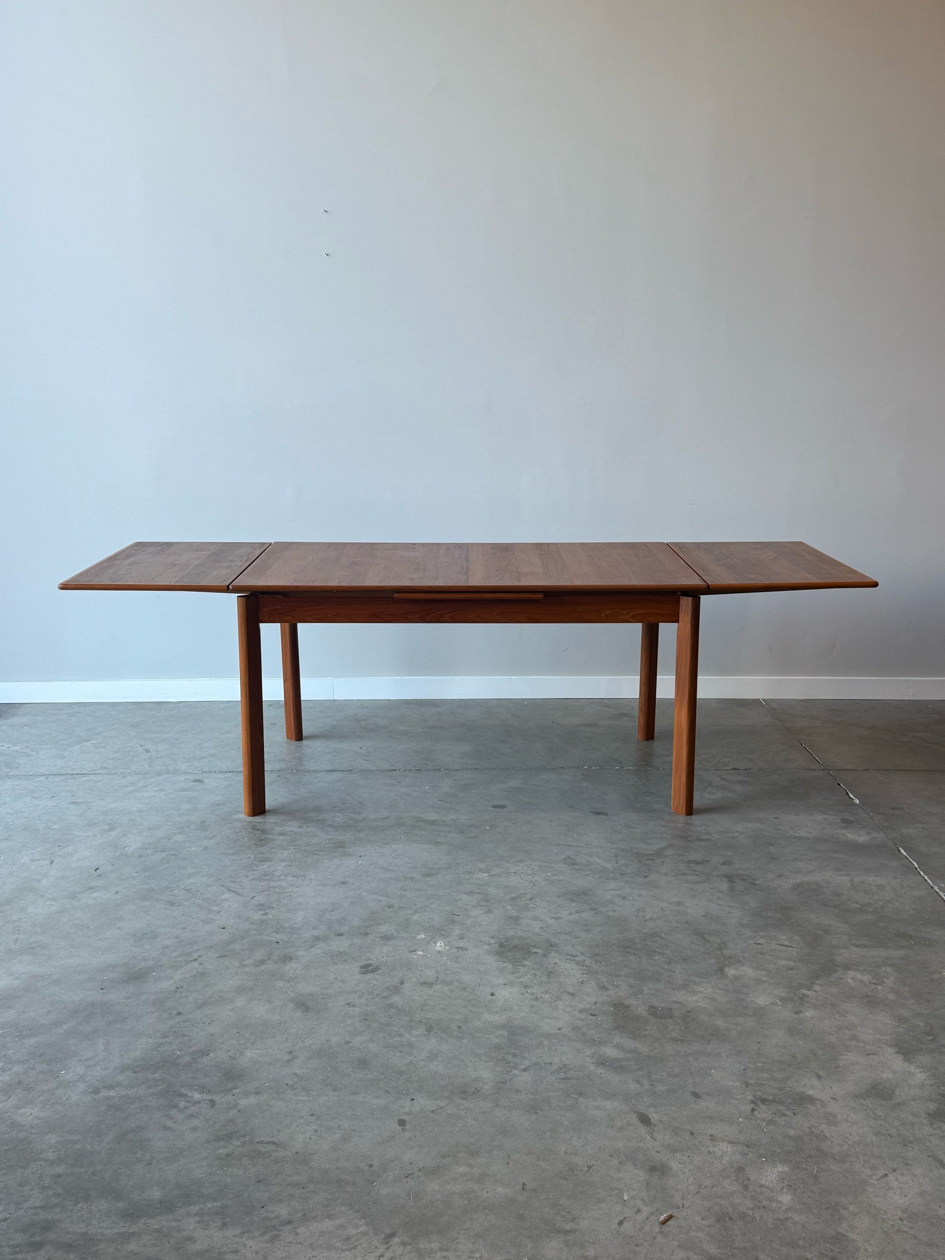 Sideways angle of a danish teak table with leaves extended