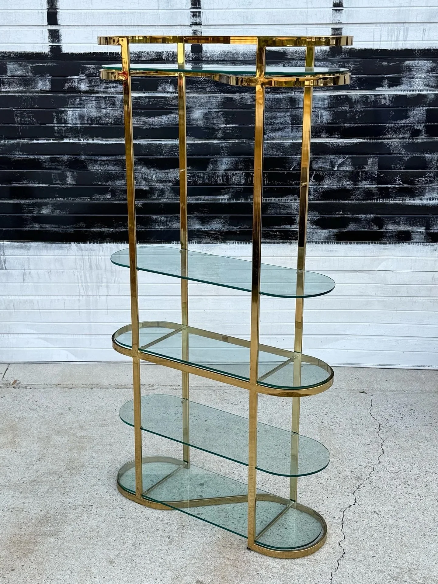 Available ~ Brass and glass etagere in the style of Milo Baughman

This piece is tall, but also quite slender which allows a perfect display without sacrificing too much floor space. Featuring five oval shaped glass inserts that create shelving. The 