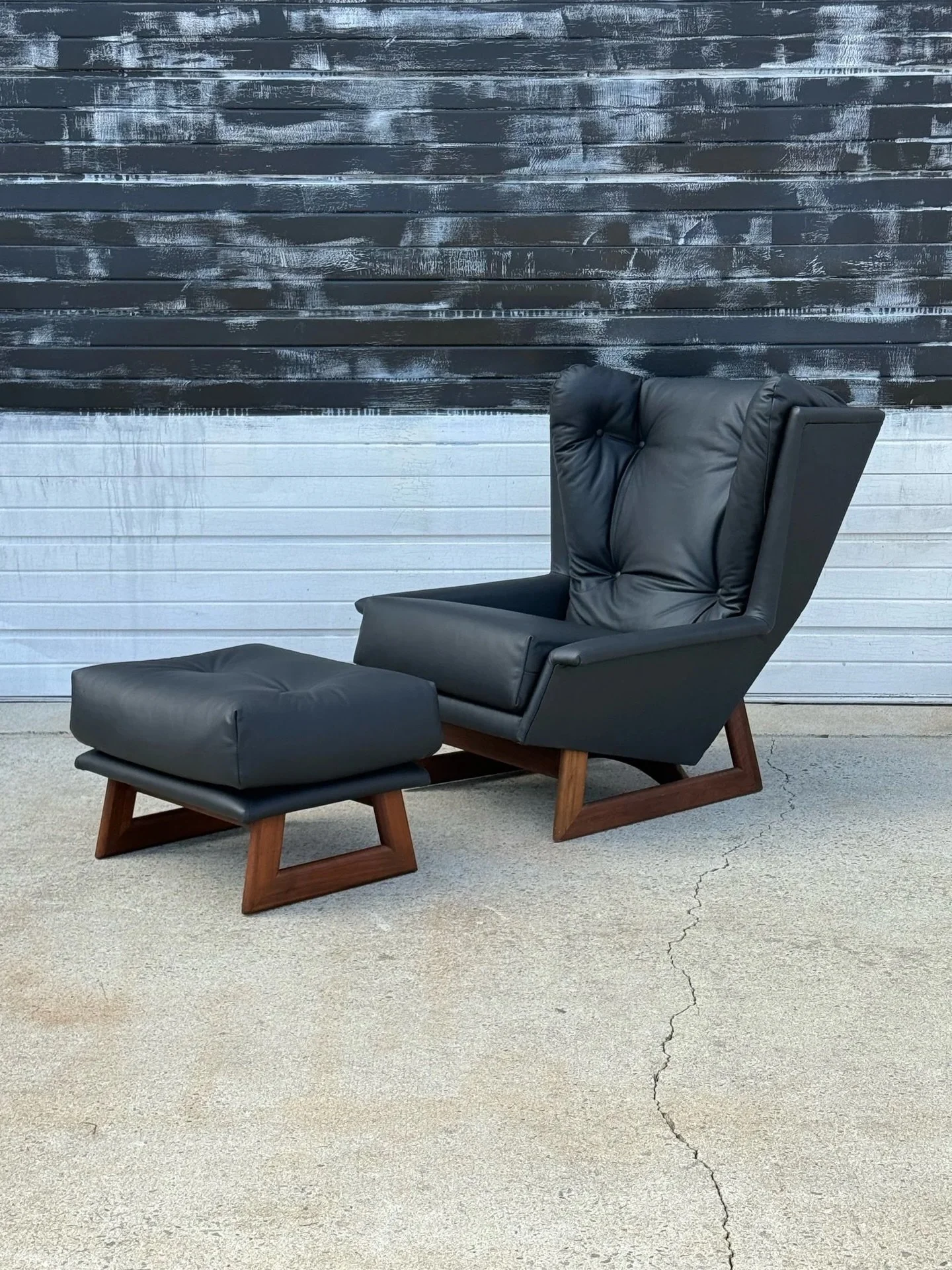 AVAILABLE ~ Mid-century wingback lounge and ottoman in black leather. Designed by Adrian Pearsall for Craft Associates, circa 1960s. 

Seldom seen, beautifully designed, and extremely comfortable. The tall back rest is angled with great cushioning. T