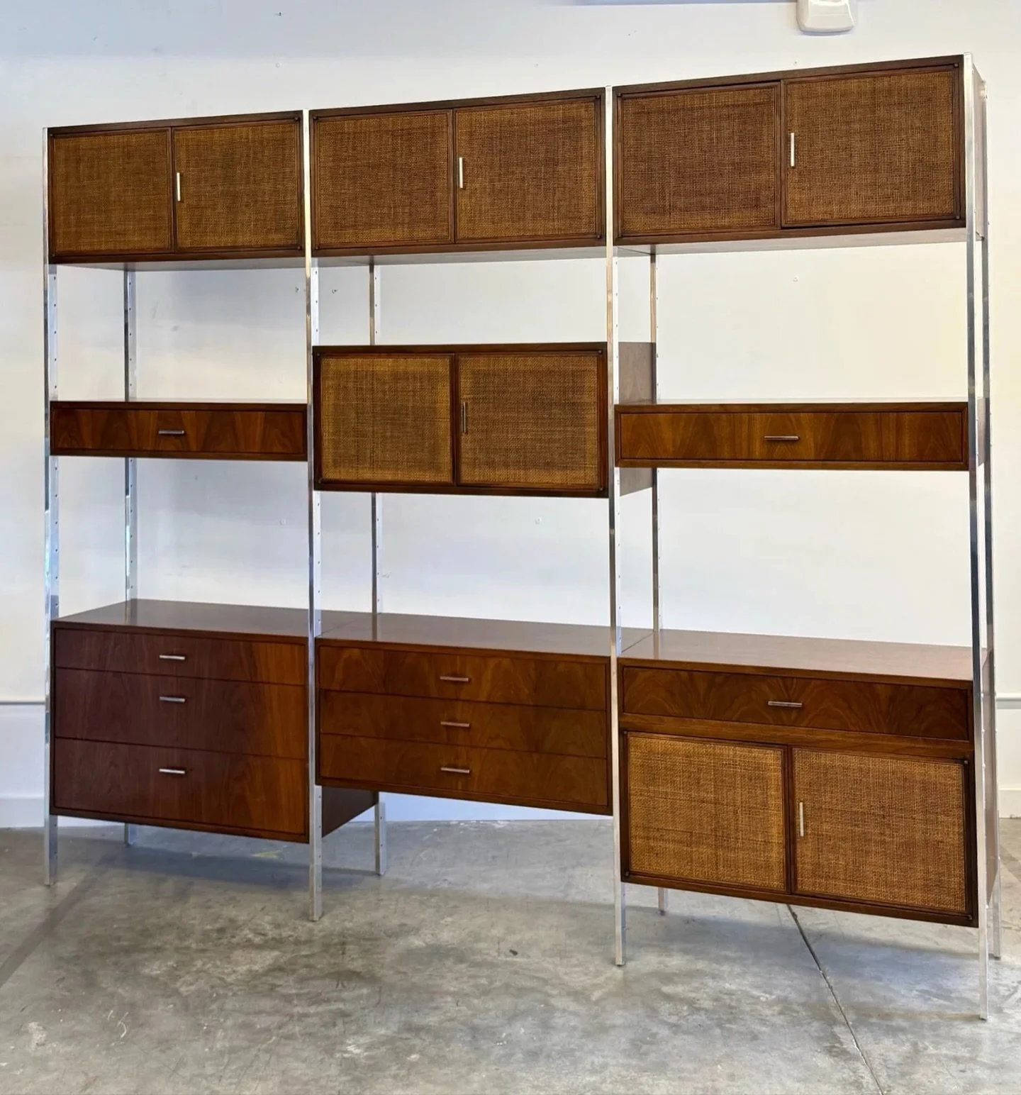 AVAILABLE ~ Mid-century three bay wall unit designed by Jack Cartwright for Founders, circa 1960s. 

This unit is made from walnut wood with cane accents and chrome supports. An incredible mix of materials that wonderfully showcases American mid-cent