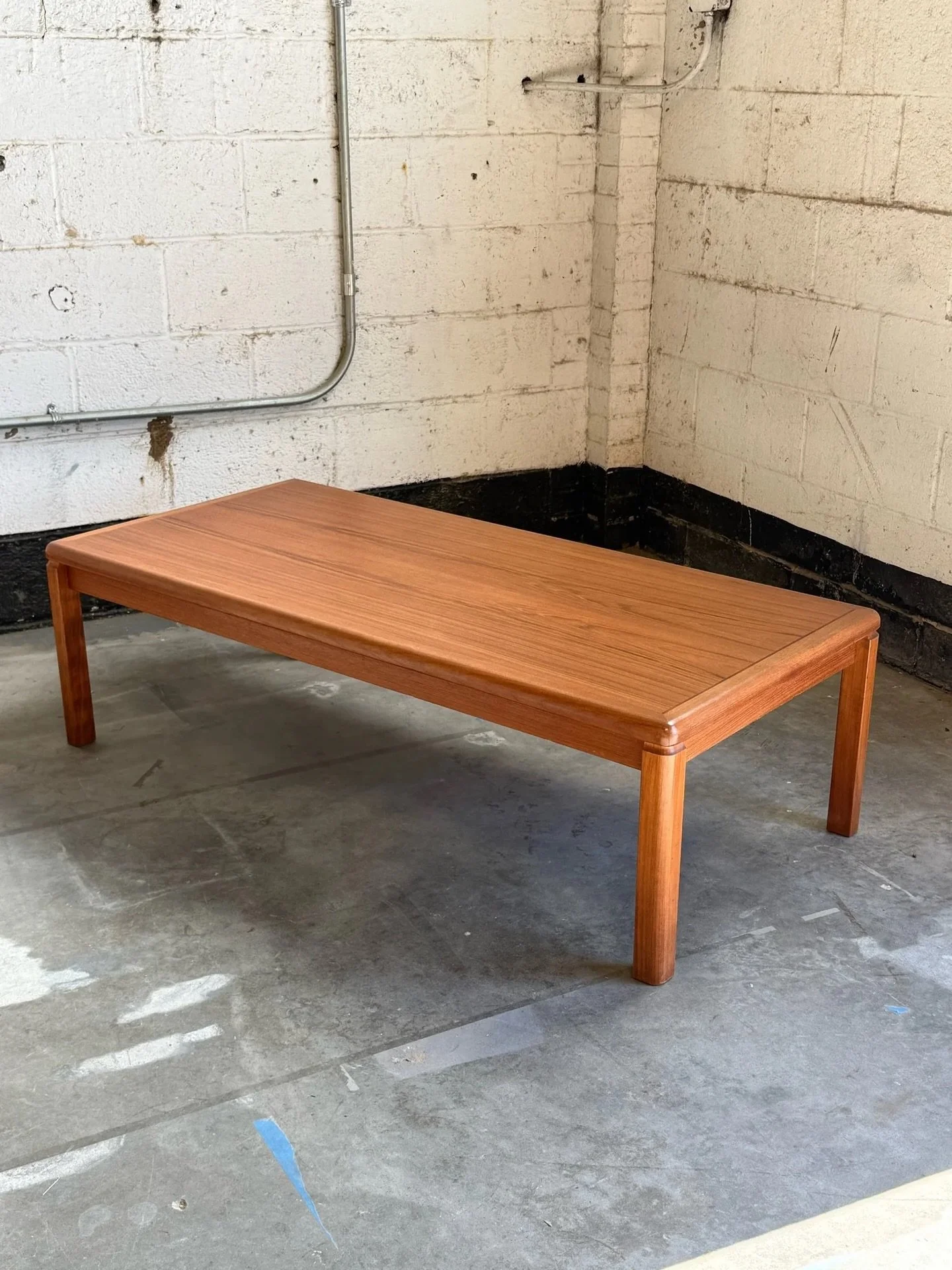 AVAILABLE ~ Mid-century rectangular coffee table. Made from teak wood, Denmark. Simple and streamlined with excellent wood grain. Nice border inlay on the top with rounded corners. Sitting atop chunky rectangular legs. In overall great vintage condit