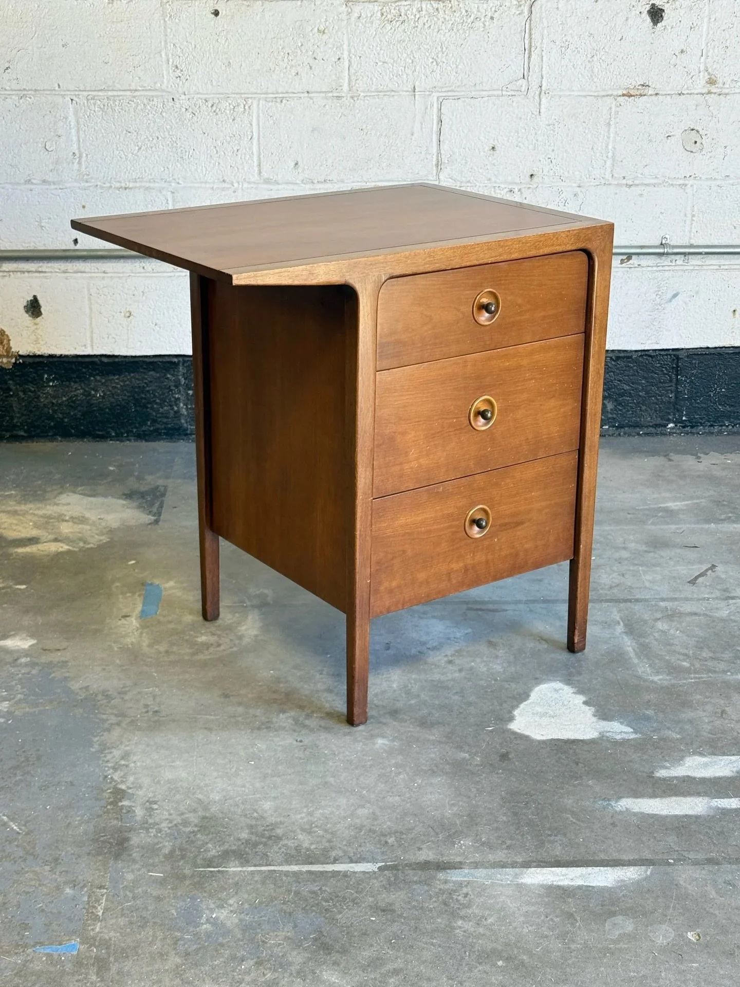 AVAILABLE ~ Mid-century bedside chest designed by John Van Koert for Drexel. This piece is a part of Drexel&rsquo;s &lsquo;Counterpoint&rsquo; line. Made from walnut wood and featuring a bank of three drawers.

Each drawer has a circular inset design