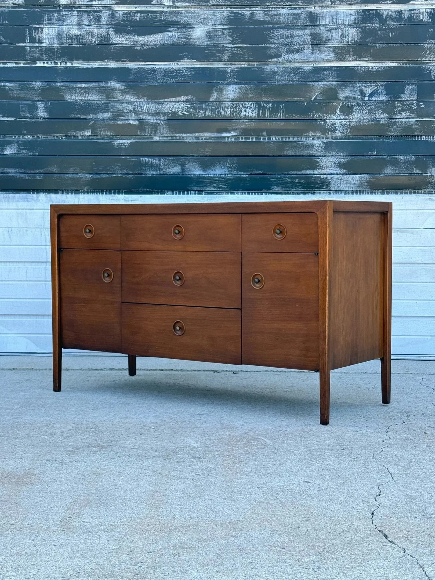AVAILABLE ~ Mid-century credenza a part of Drexel&rsquo;s &lsquo;Counterpoint&rsquo; line designed by John Van Koert. 

This piece is crafted from walnut wood featuring five drawers, three align the top and two divide the middle of the credenza. Two 