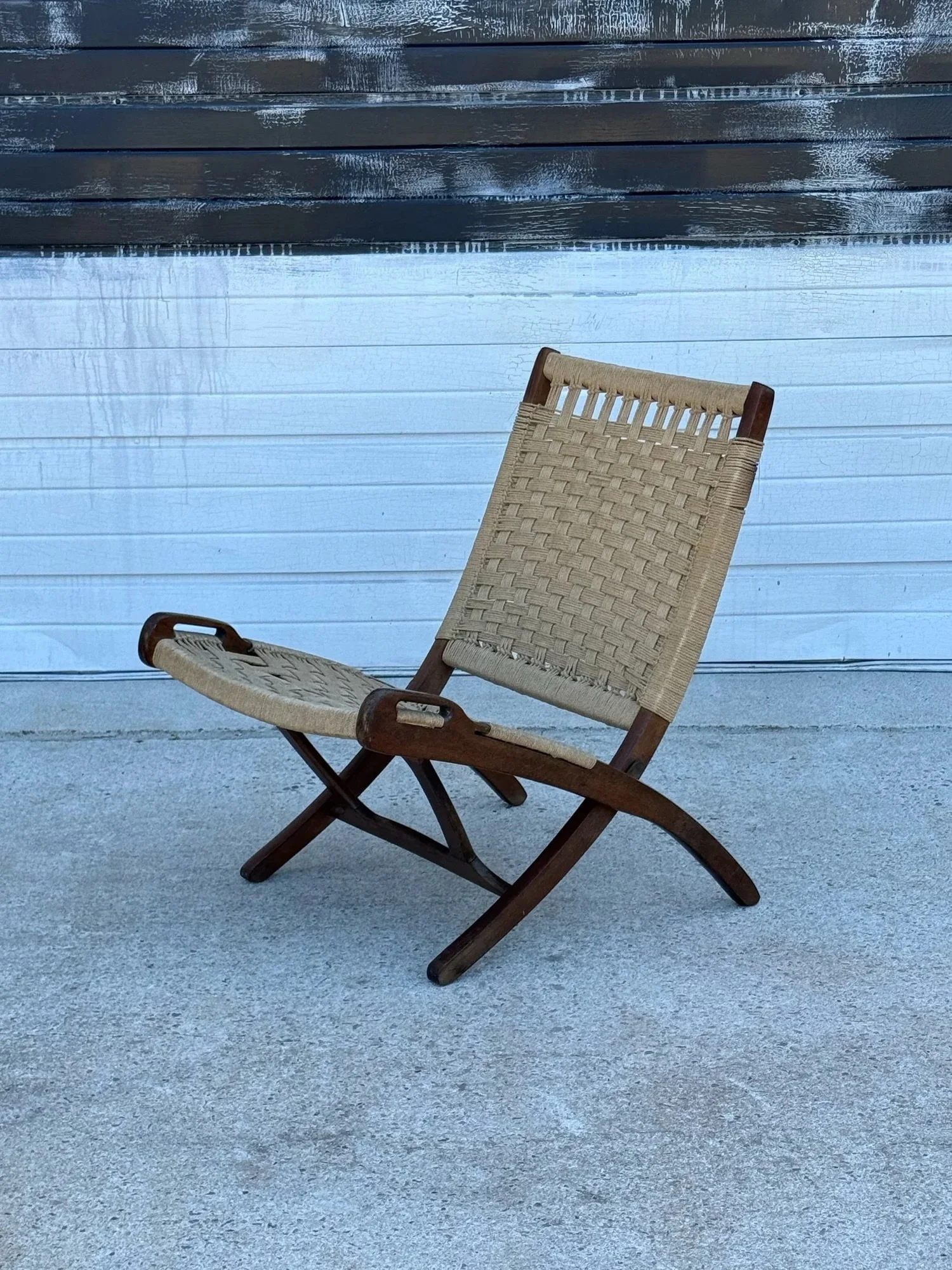 Mid-century folding chair by Hans Wegner. The frame is wooden while the seat and back feature the original woven rope. 

The woven rope coloration is a neutral tan. The chair folds for easy carrying and easy storage. The wooden frame is shaped like a