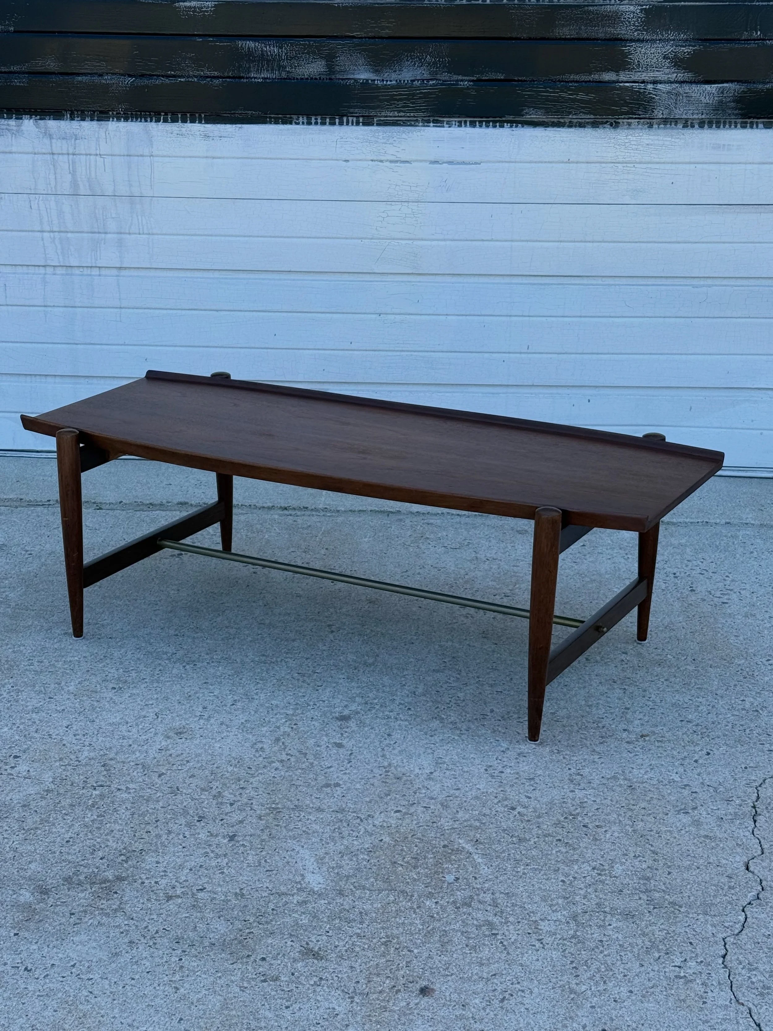 AVAILABLE ~ Mid-century surfboard coffee table. Made in Denmark from teak wood, circa 1960s. This coffee table is quite unique and displays excellent craftsmanship.

The top is rectangular with raised edges. Supported by teak tapered legs that are ro