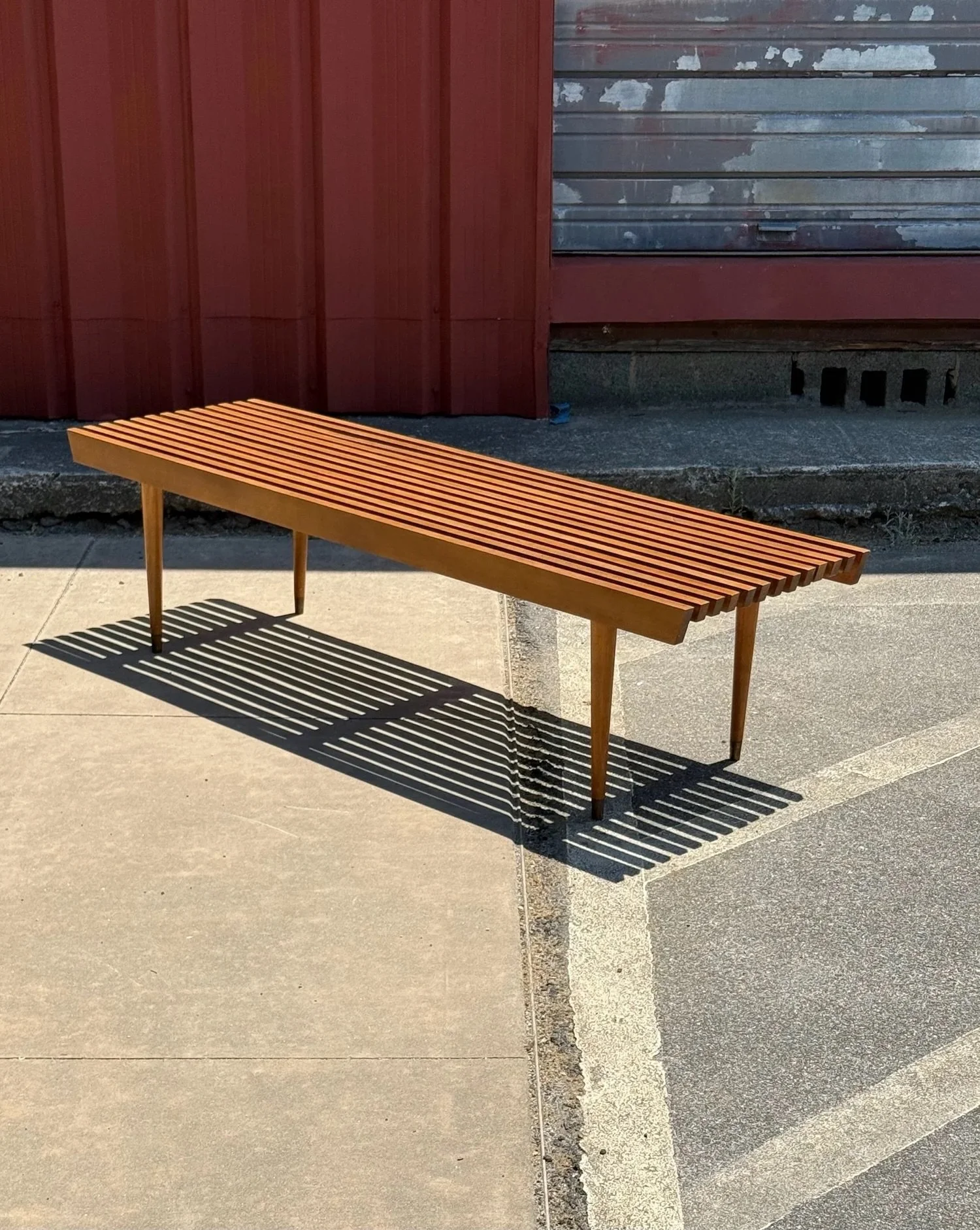 AVAILABLE ~ Vintage classic style slat bench. Rectangular in shape with a walnut finish. 

Sitting atop four tapered legs with brass capped feet. This item would be perfect as a coffee table, entryway bench, or plant stand. In overall great vintage c