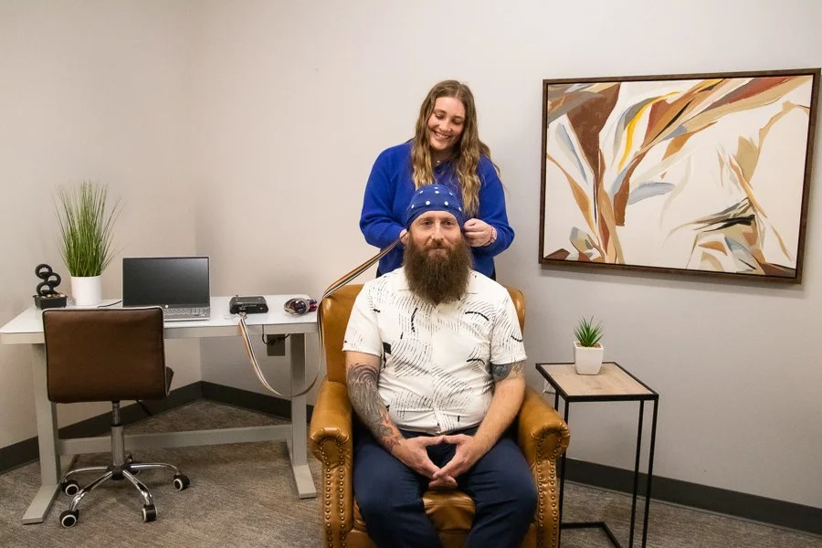 Female provider placing neurofeedback cap on male patient.