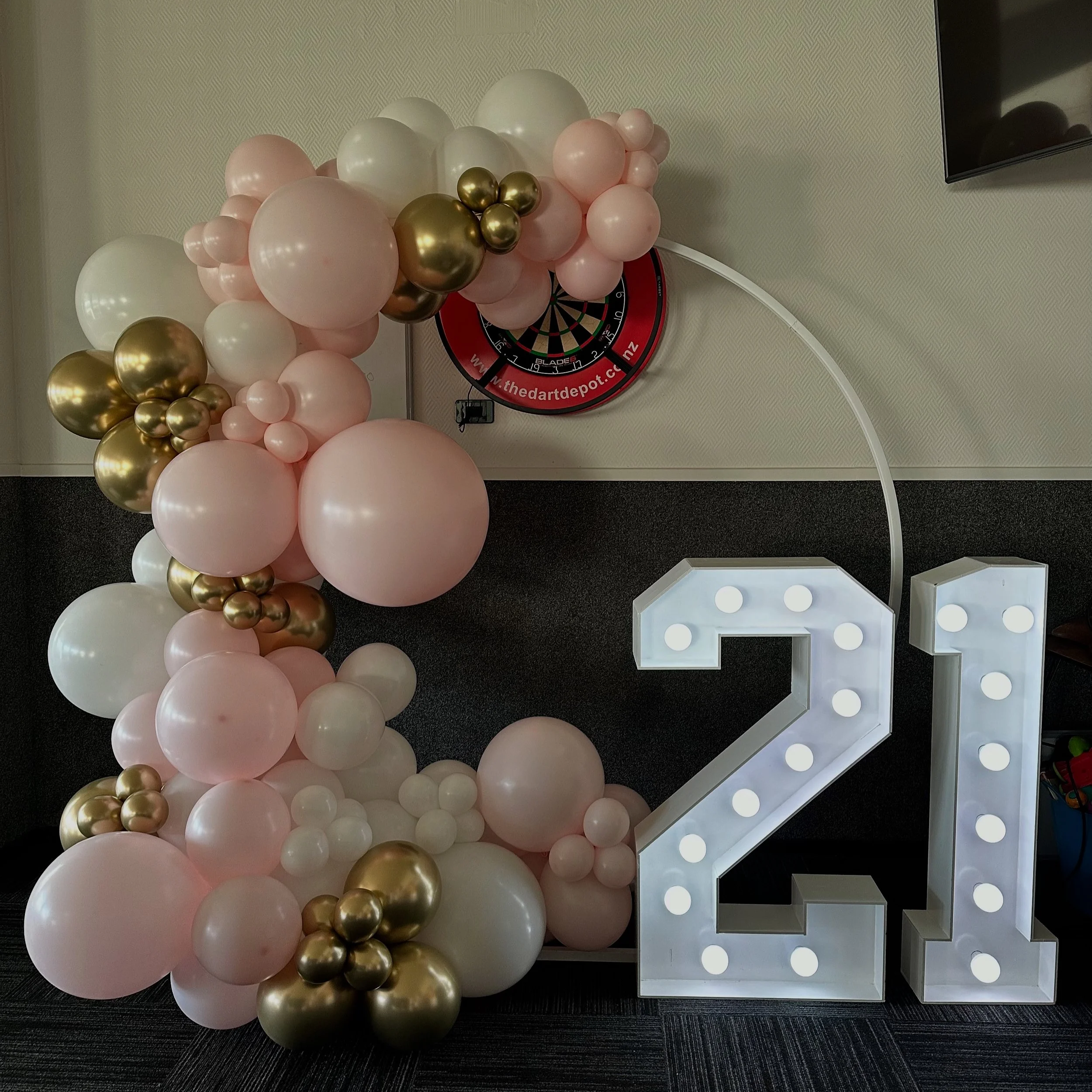 Decorative balloon arrangement in shades of white, blush, green, with a large illuminated number 30 sign beside it.