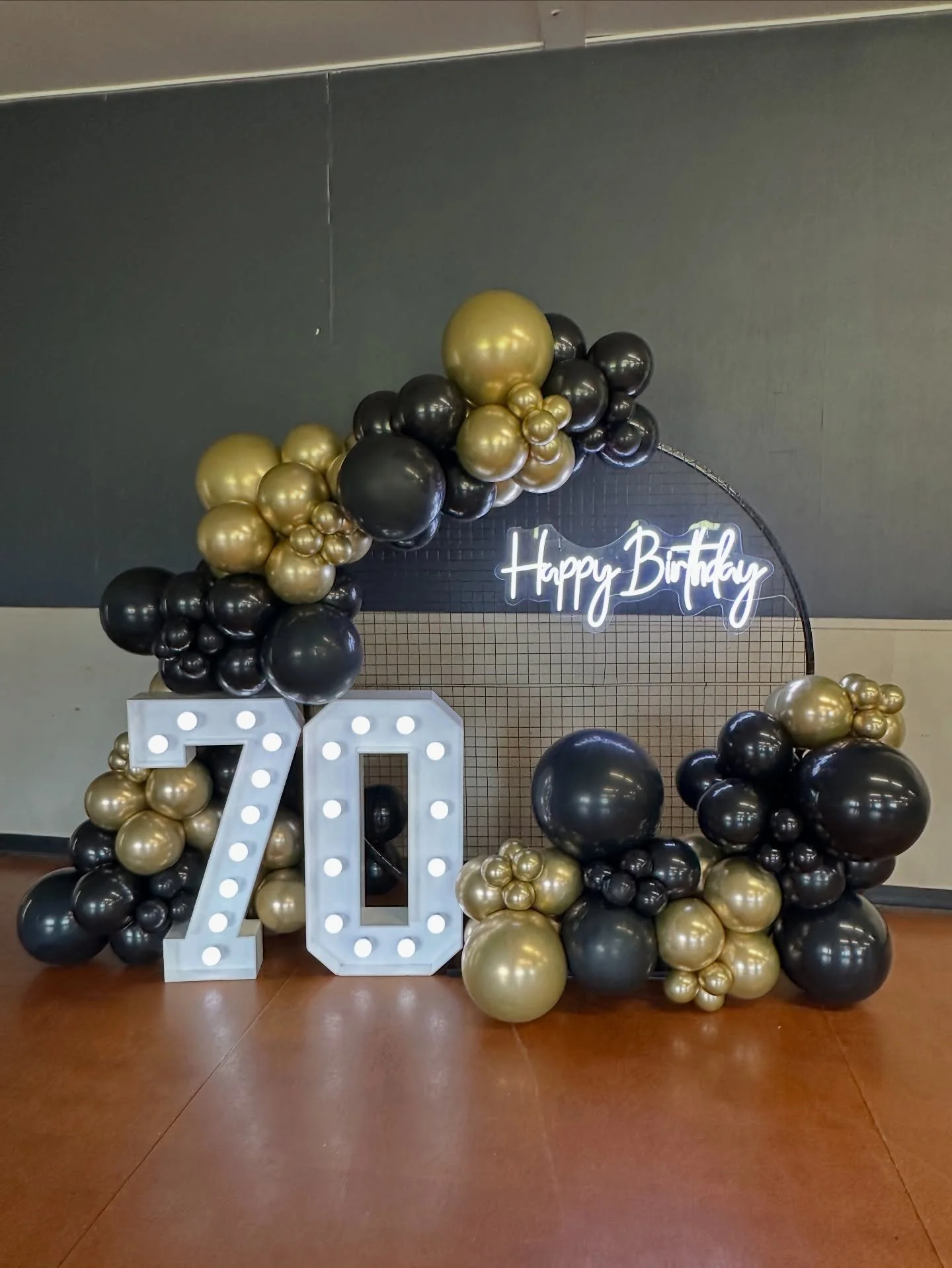 ✨ Celebrating 70 in Style ✨

A milestone birthday deserves a statement setup &mdash; and this one delivered 🖤💛
Black circle mesh frame styled with luxe black &amp; gold balloons, marquee 70 number lights, and a glowing Happy Birthday neon to finish