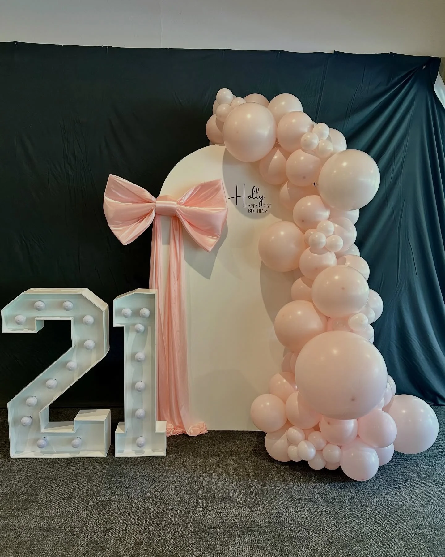 Soft pink elegance for a special 21st celebration 💗✨

This beautiful setup featured a white arch wall with a custom decal, styled with a large light pink bow and a cascading arrangement of pastel pink balloons. Finishing the look were the ever-popul