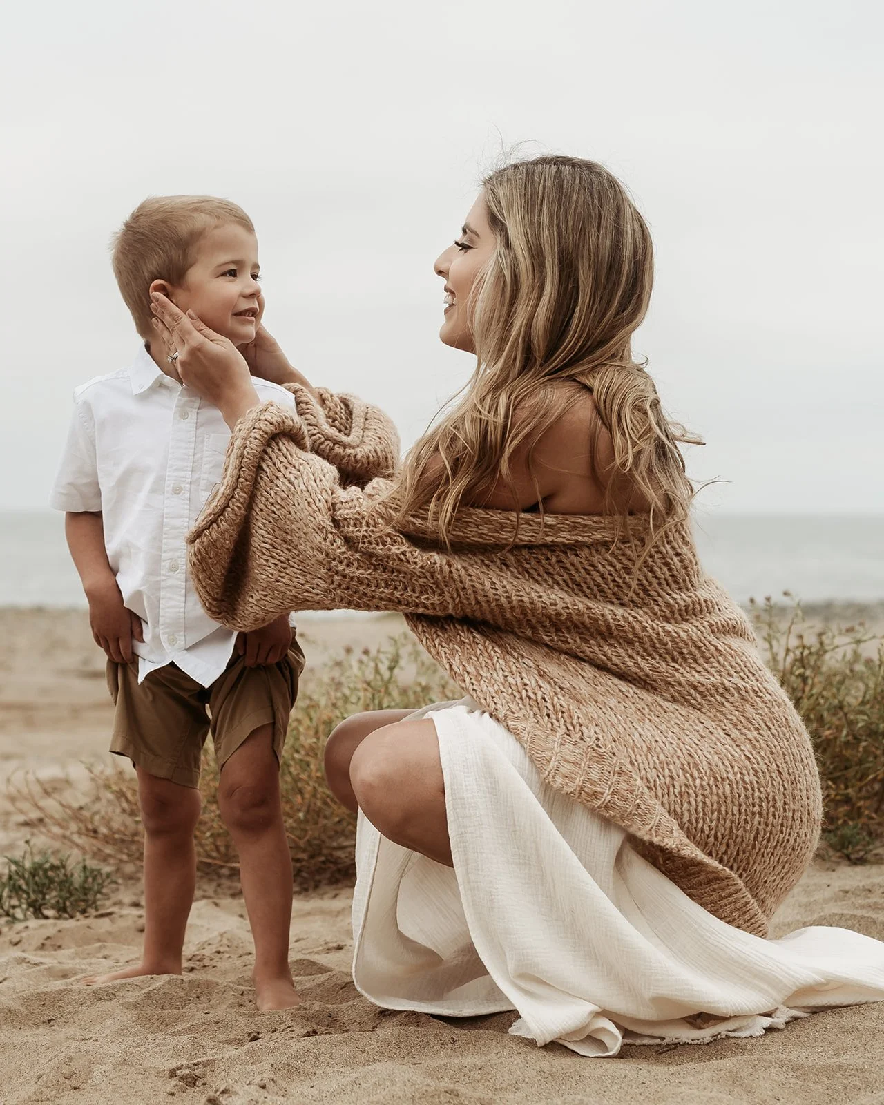 Southern California family photographer captures mother holding her sons face on the rocky beach in san Clemente California.