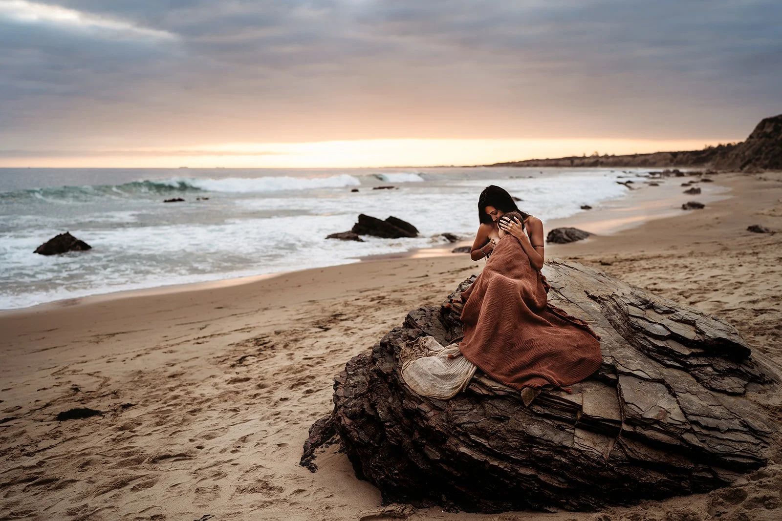 Southern California family photographer captures mother and daughter breastfeeding on rock in Newport Beach California.