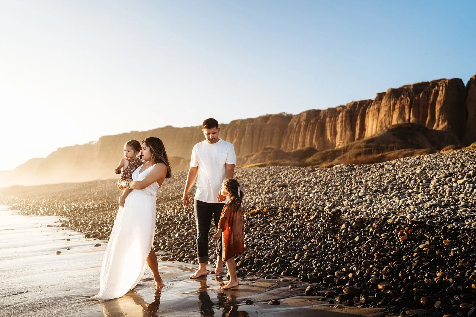 Southern California family photographer captures family on the rocky beach in san Clemente California during a sunset session.