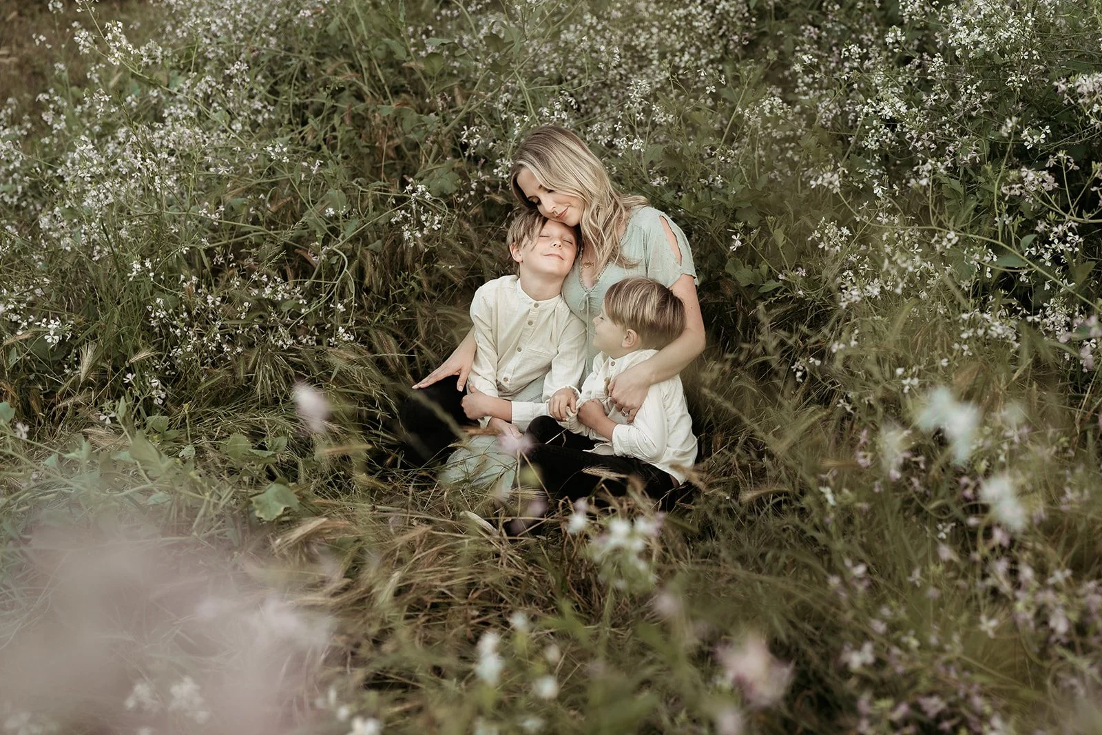 Southern California family photographer captures mother snuggling sons in the flowers at gum grove park near Long Beach California.