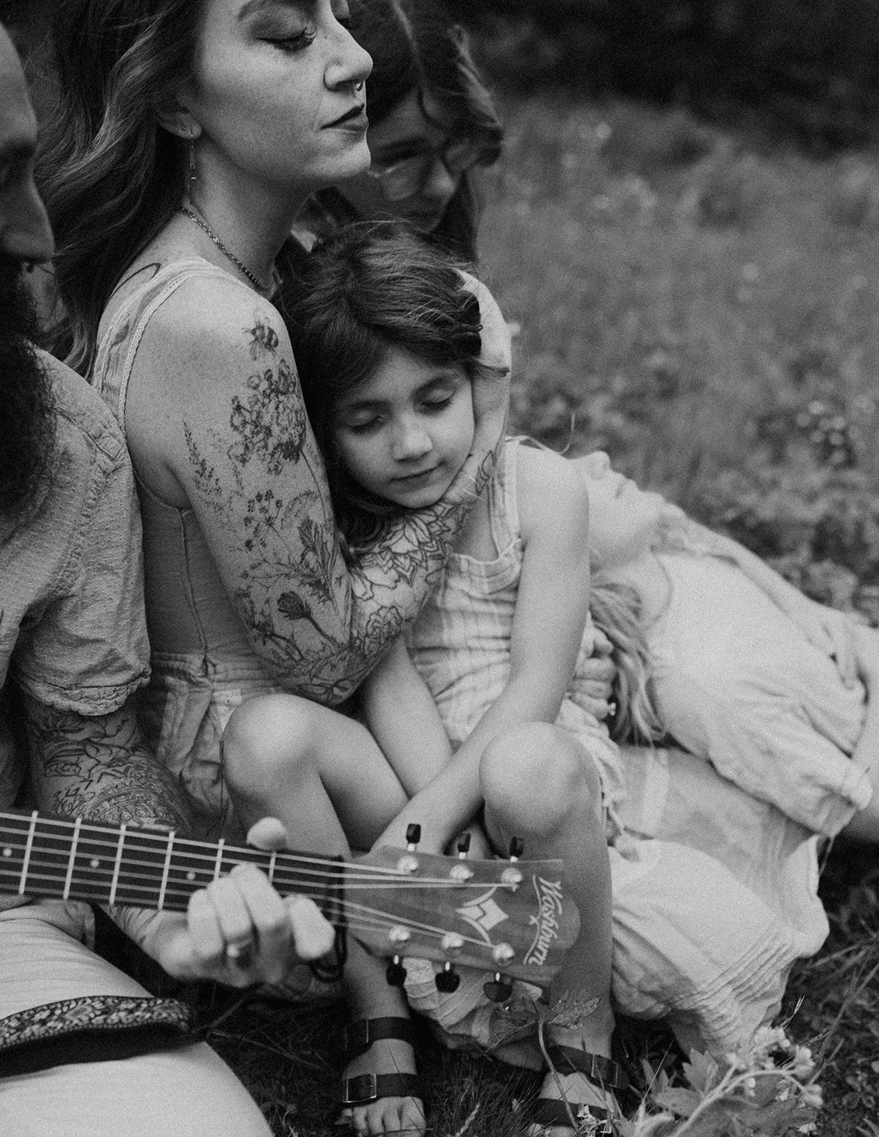 glacier national park family photographer captures mother snuggling son with listening to her husband play the guitar near two medicine lake Montana in east glacier.