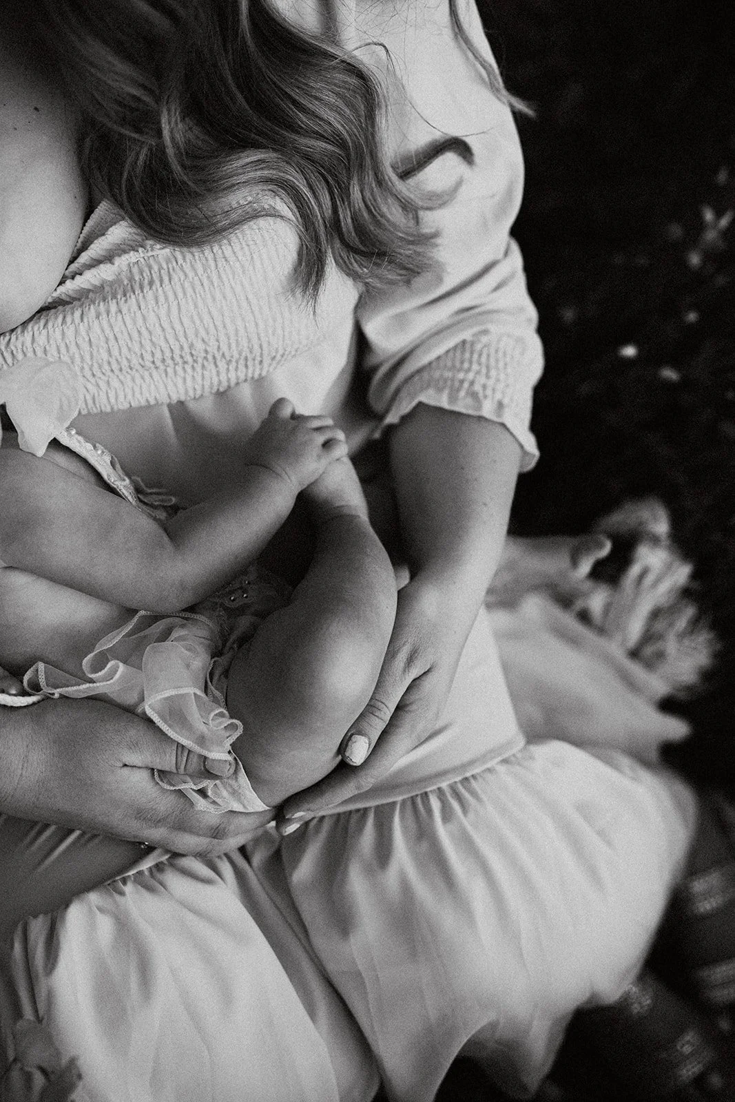 Southern California family photographer captures mother holding daughter while she breast feeds in a poppy covered field in riverside California.