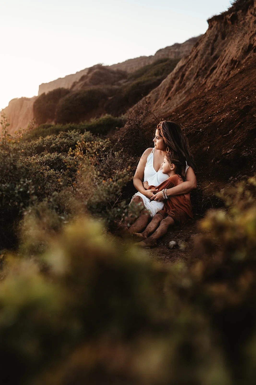 Southern California family photographer captures mother snuggling daughter in the greenery of san Clemente California.