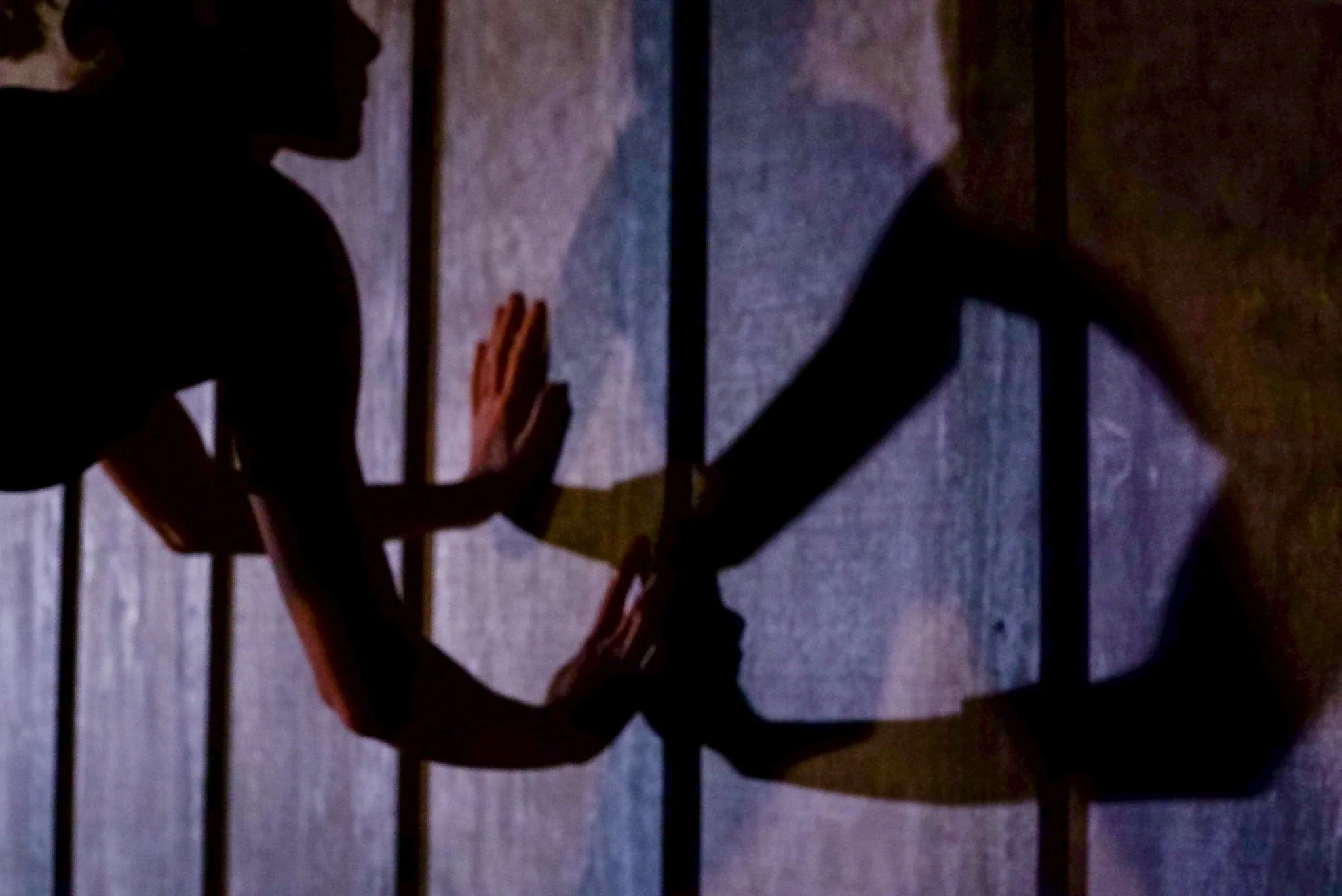 Silhouette of a person practicing yoga against a wall with shadows cast by a light source.