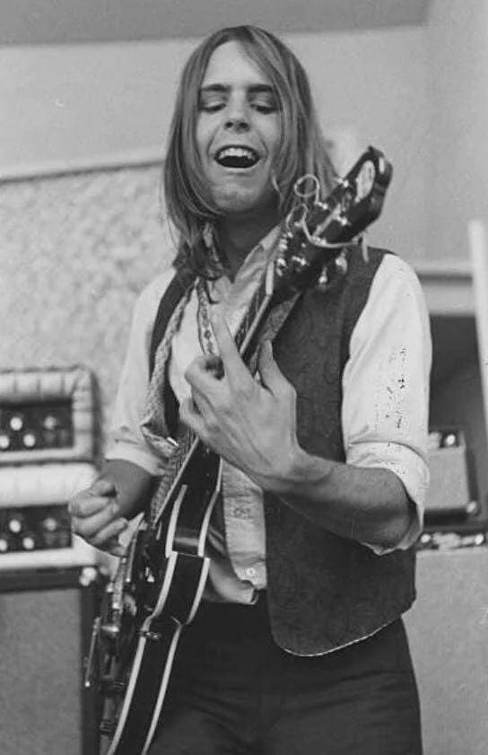 A man playing guitar and smiling