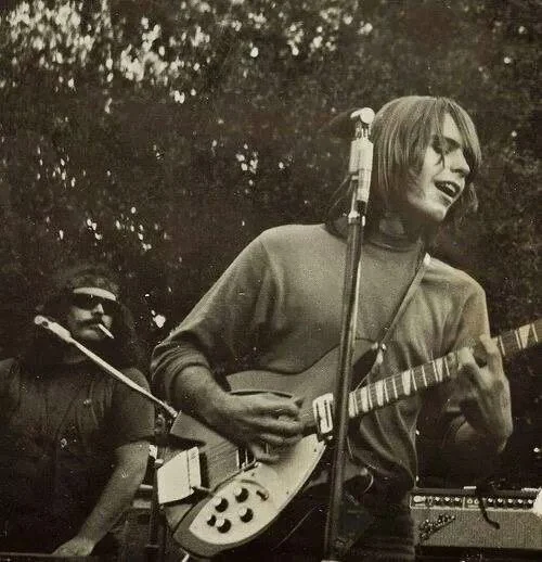A man smiling and playing guitar